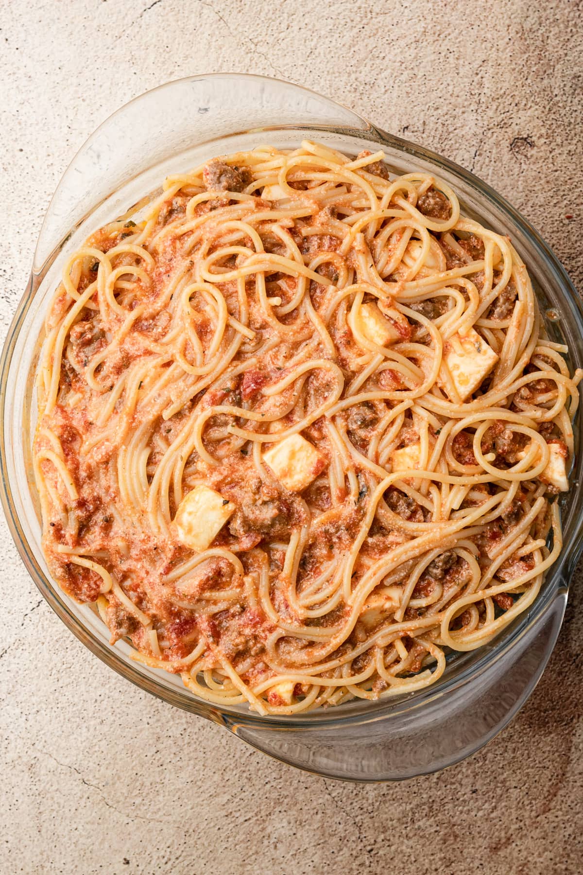 An unbaked spaghetti pie with mozzarella, marinara and sausage.