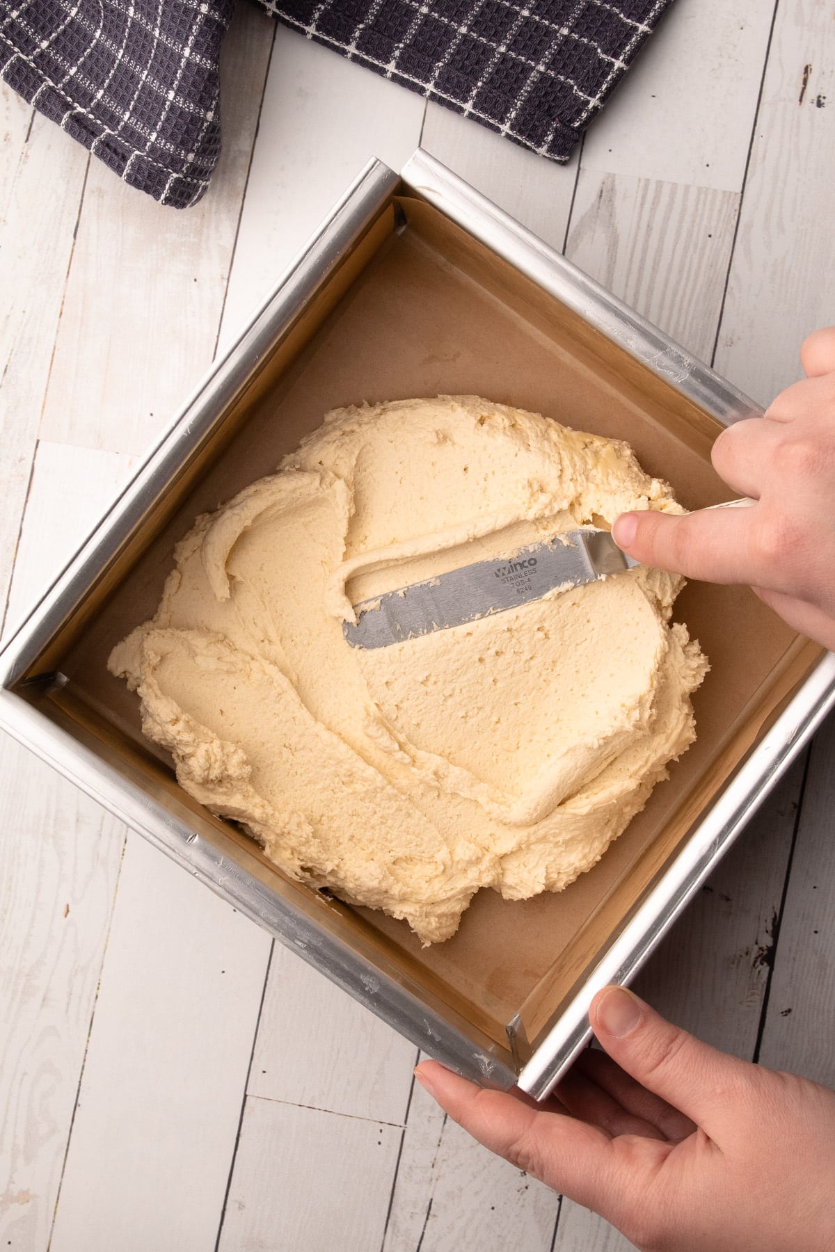 Patting the biscuit dough into the metal pan to make ted lasso shortbread biscuits.