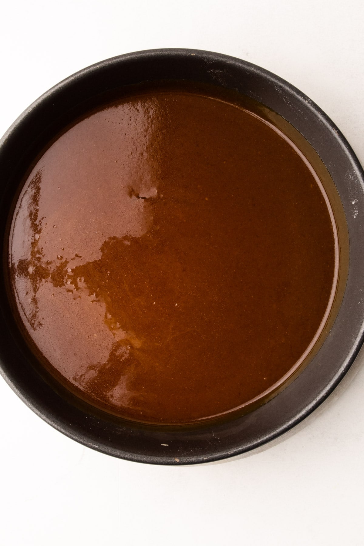 Apple cider caramel in a cake pan in preparation for apple tarte tatin.