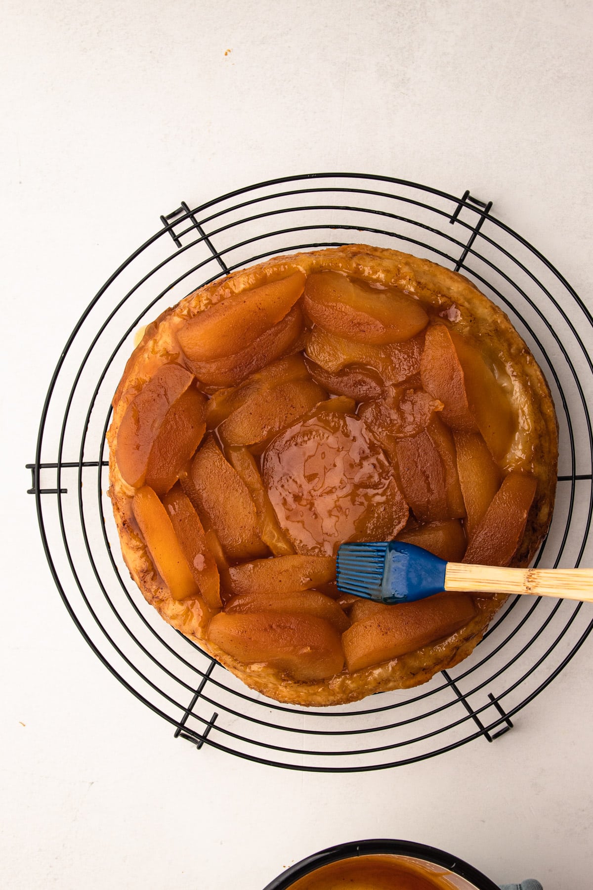 Brushing apple cider caramel on top of apples for apple tarte tatin.