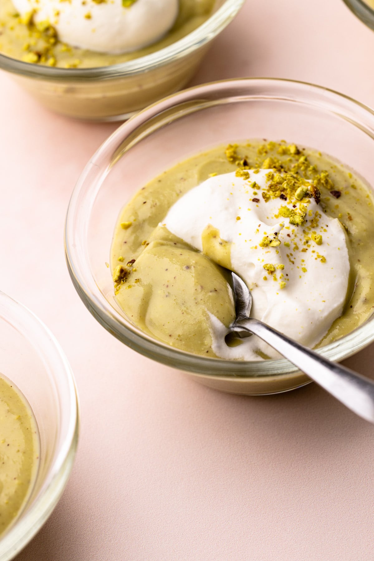 A bowl of pistachio pudding with whipped cream and chopped pistachios.