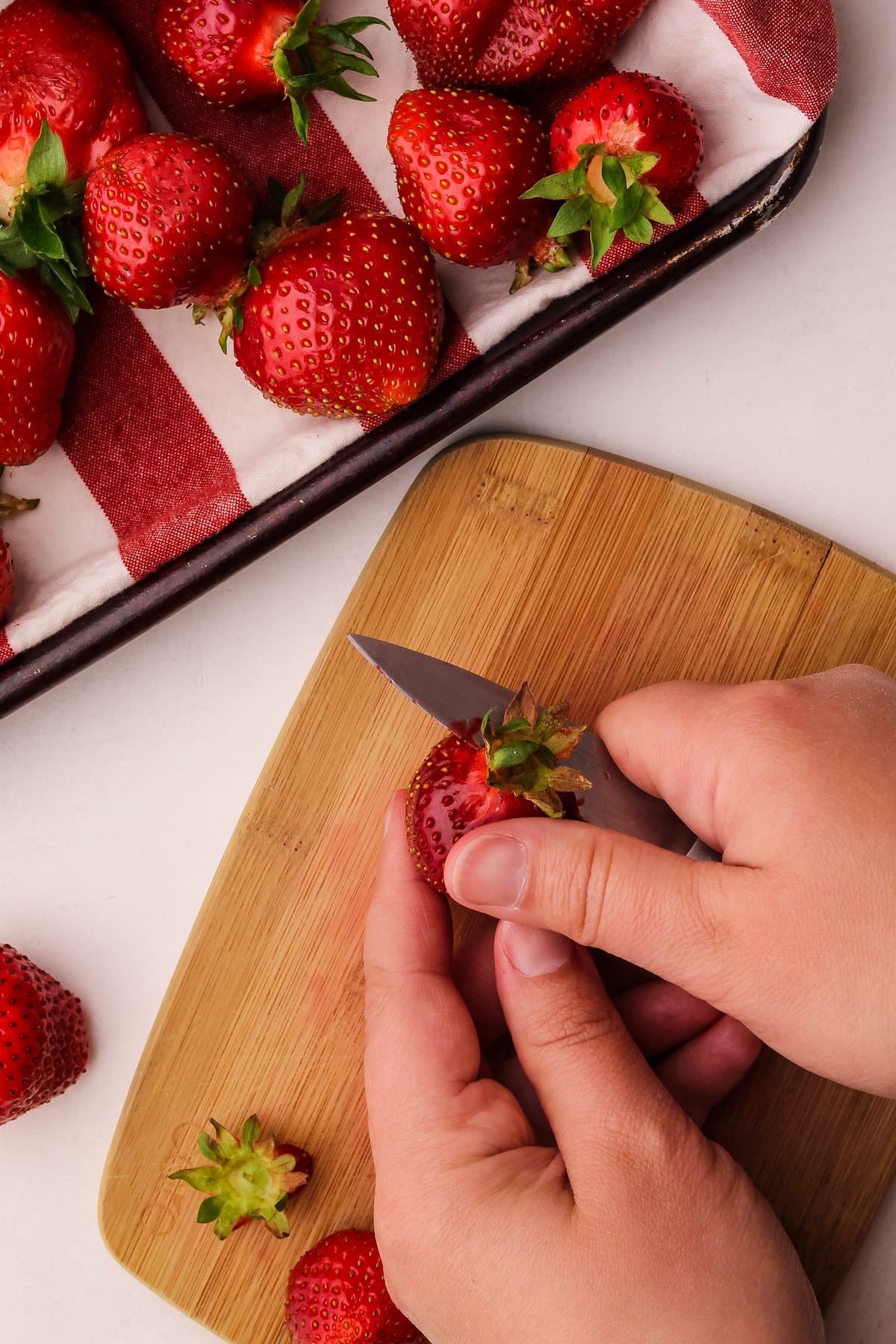 Preparing strawberries by washing, drying and hulling them.