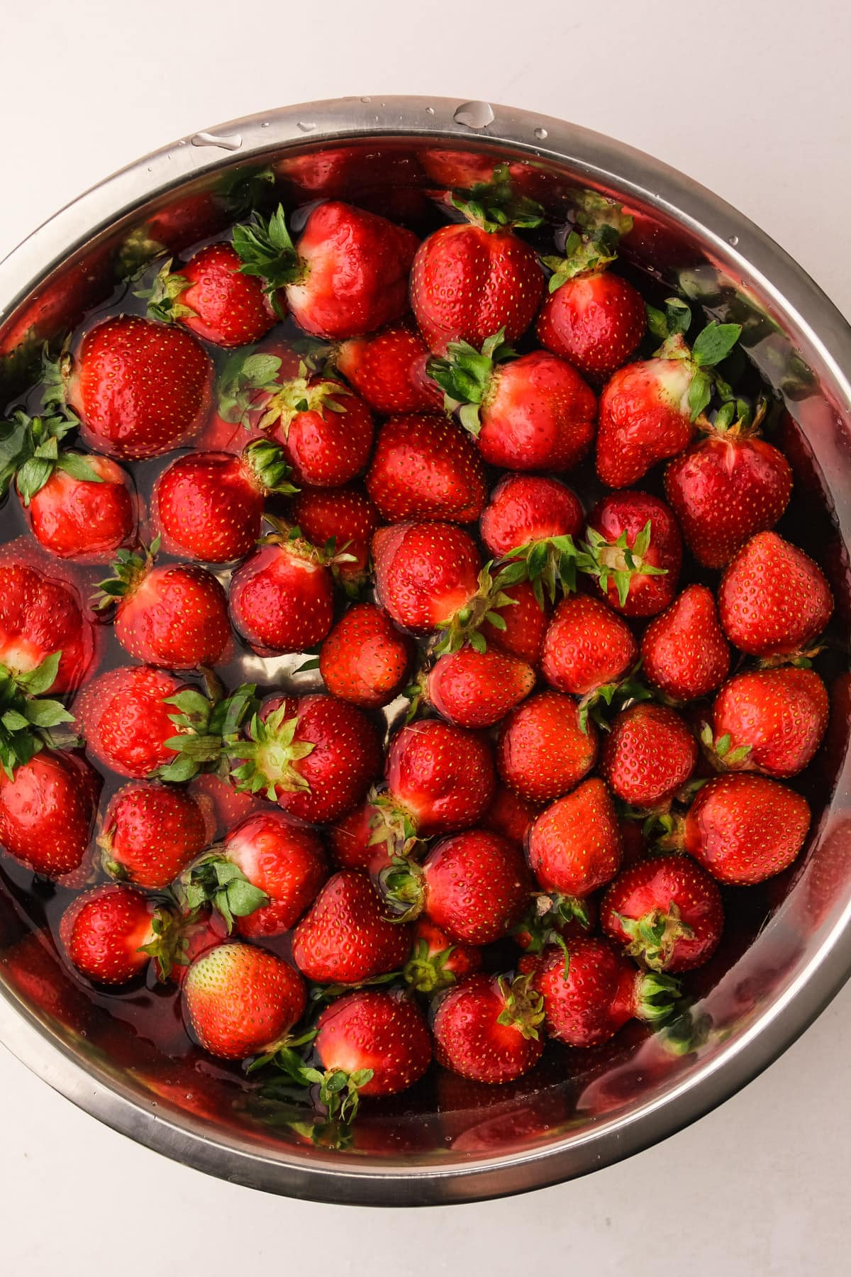 Strawberries in a bowl getting cleaned.