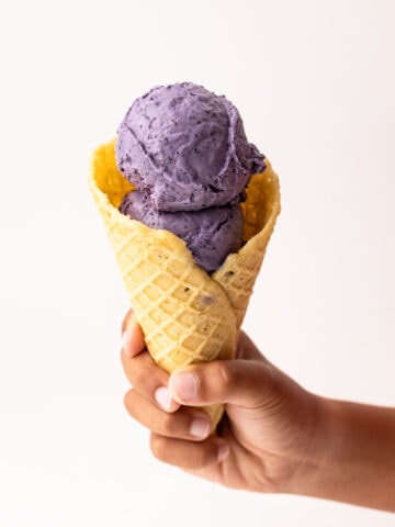 A scoop of blueberry ice cream in a cone.