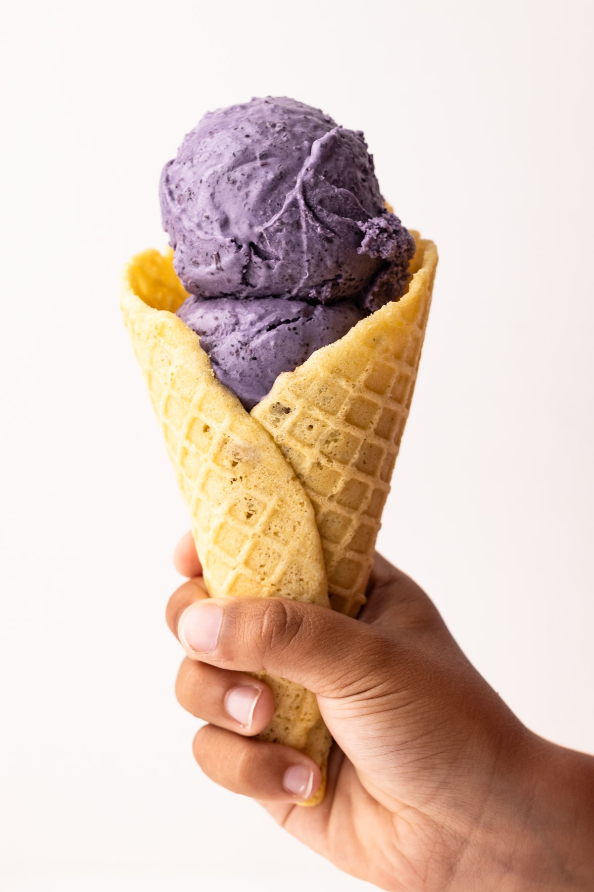 Blueberry ice cream in a waffle cone.