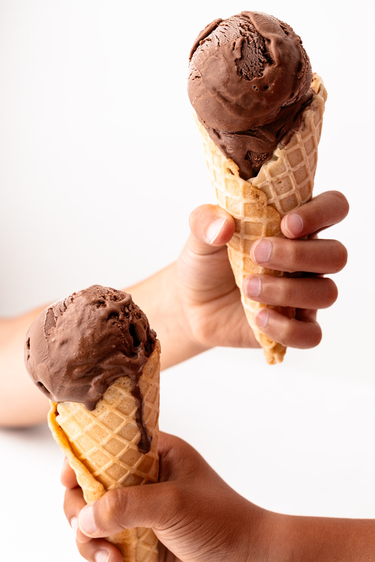 Two little hands holding chocolate ice cream.