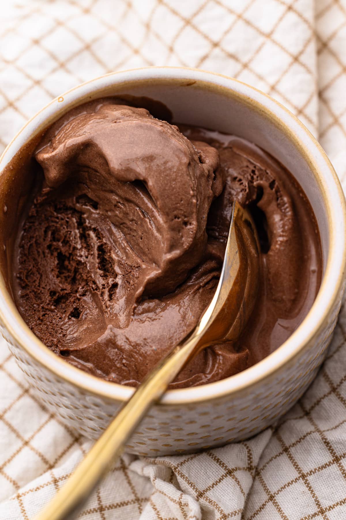 A bowl of chocolate ice cream with a scoop taken out.