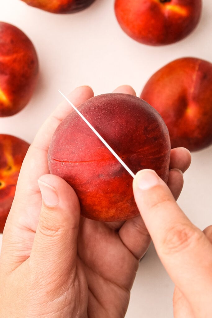 Cutting an x in a peach to blanch it.