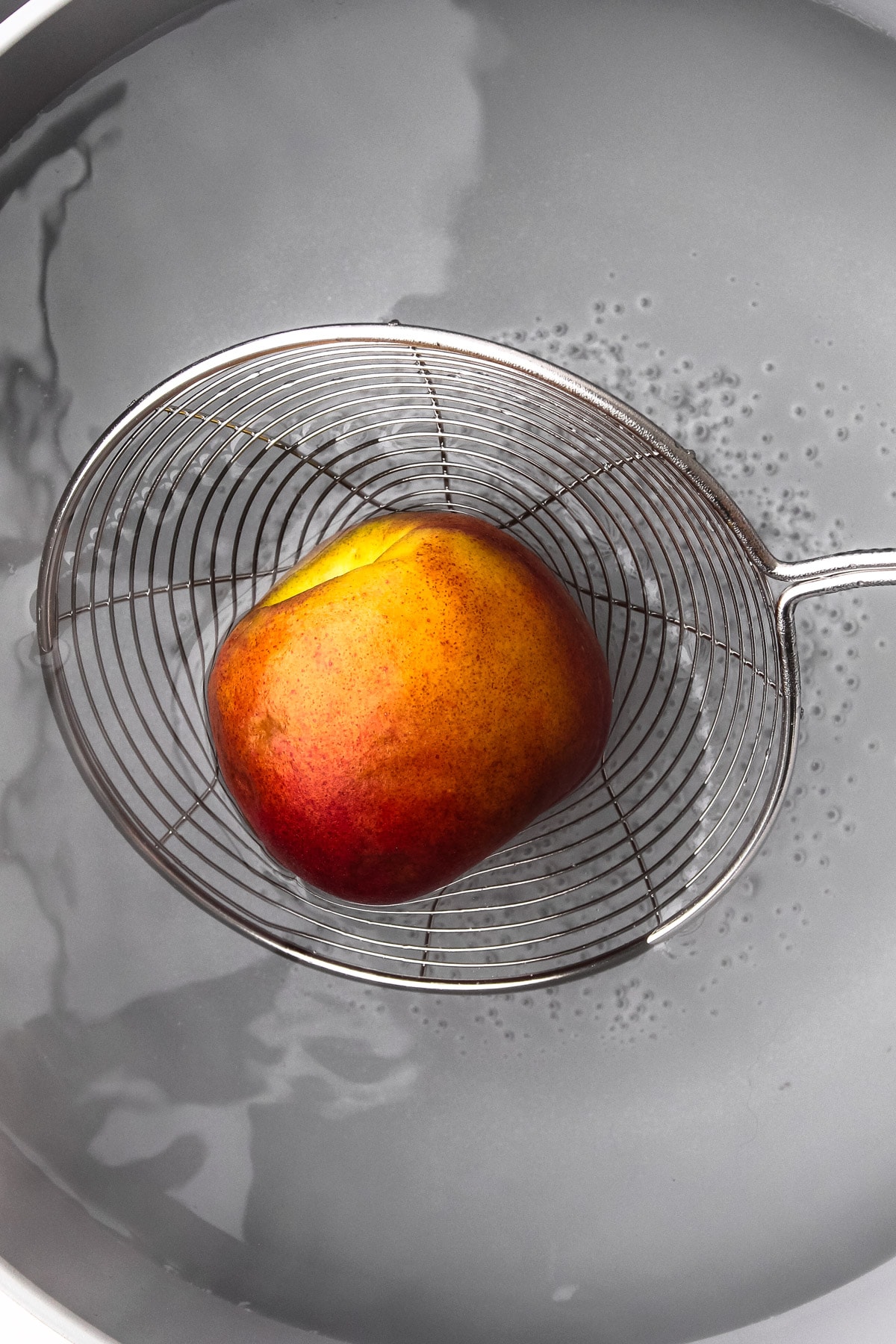 Blanching a peach to peel the skin.