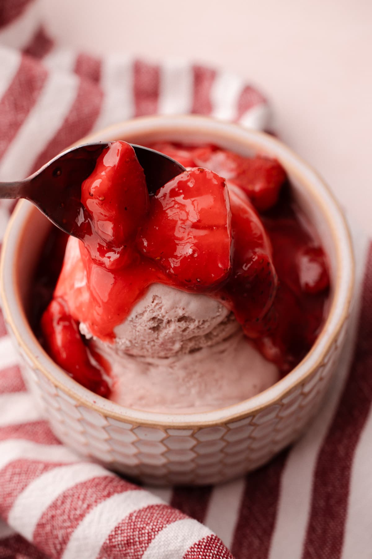 A serving of homemade strawberry ice cream with strawberry topping.