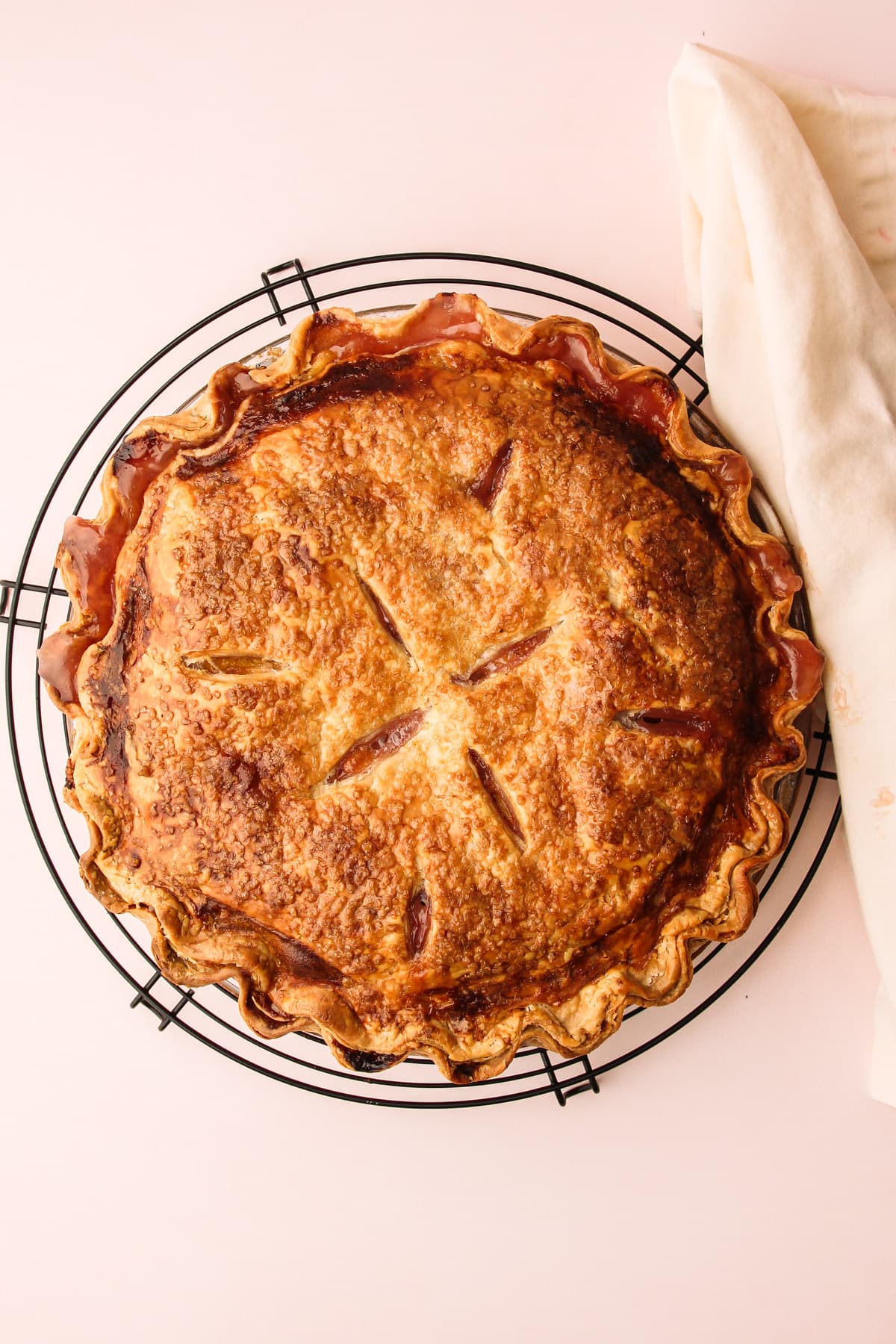 A baked peach pie on a cooling rack.