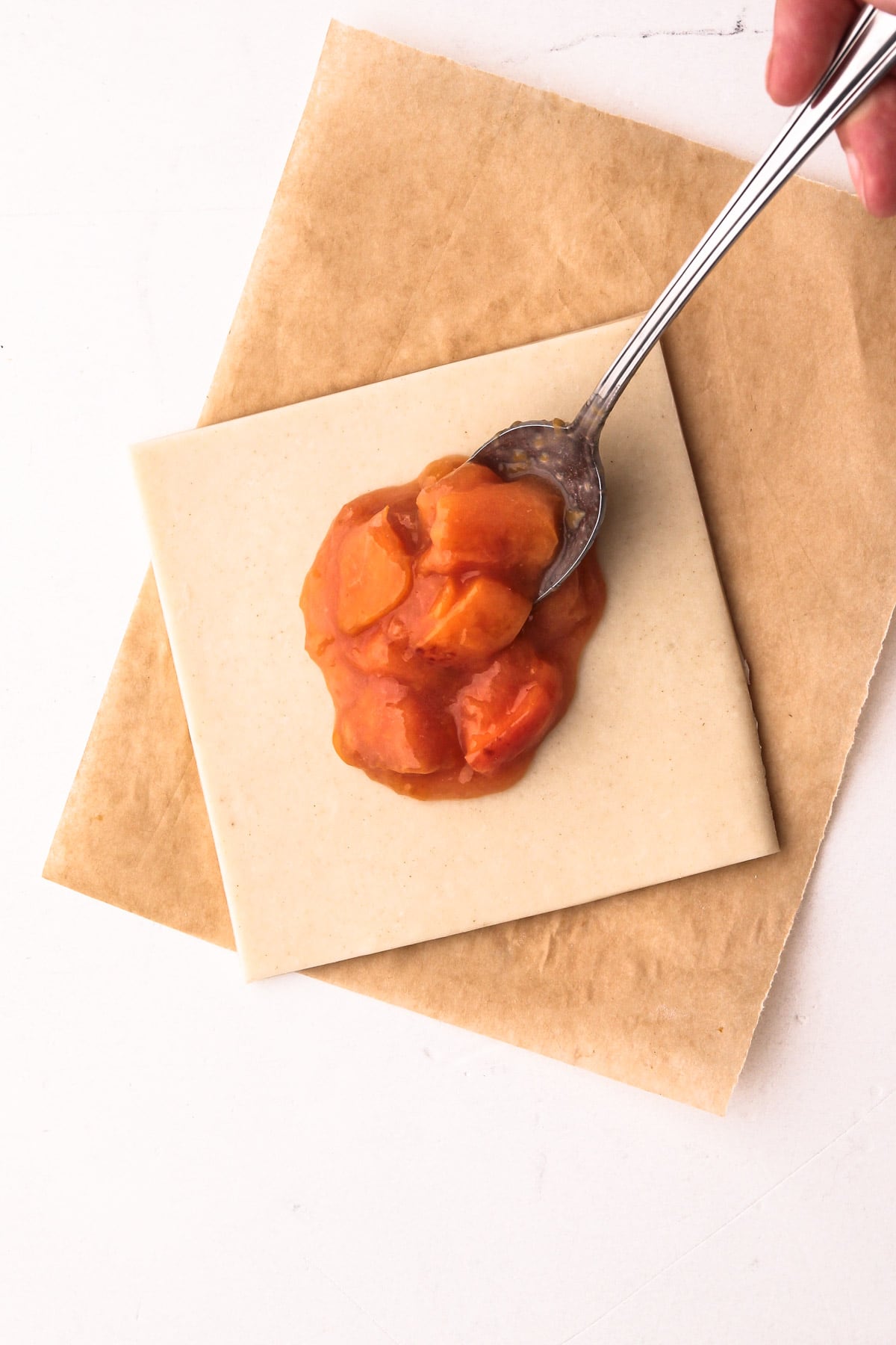 A spoonful of peach filling on a square of pastry.