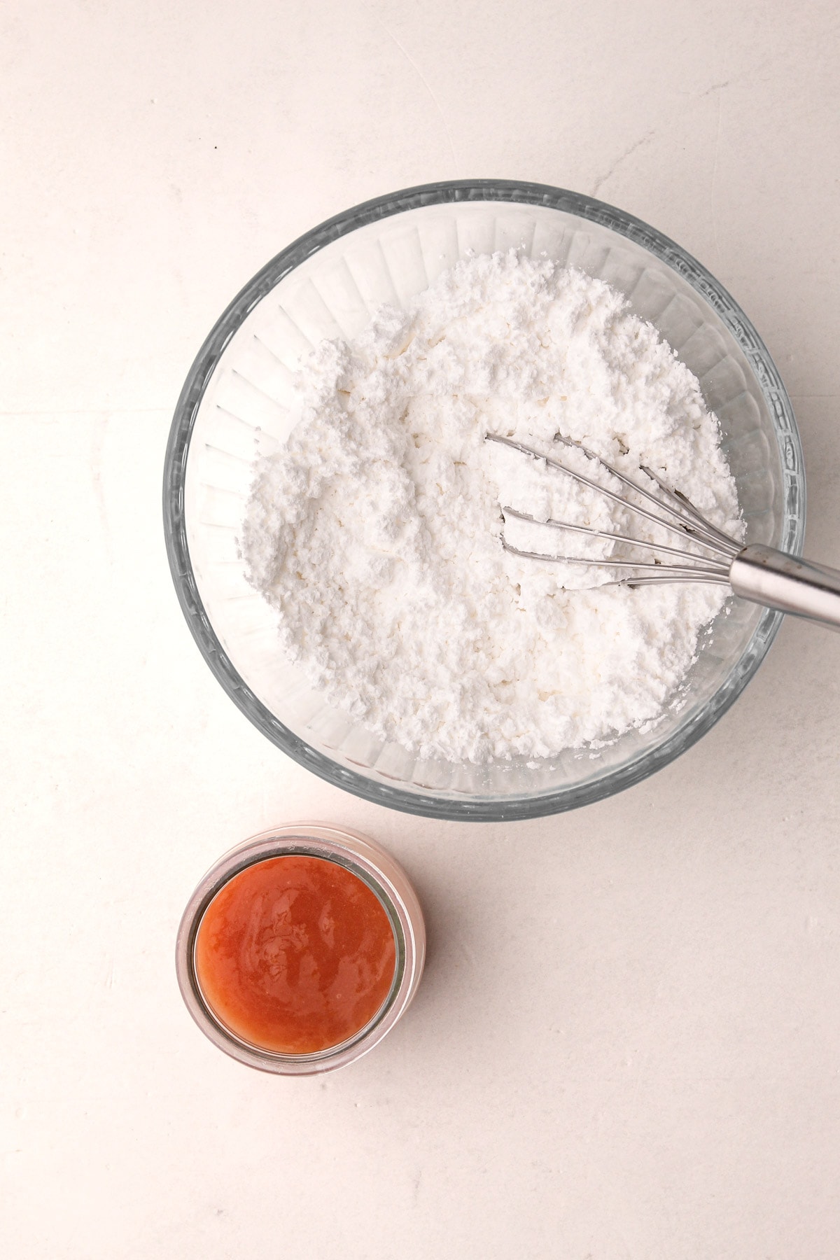 A bowl of powdered sugar and a container of peach filling.