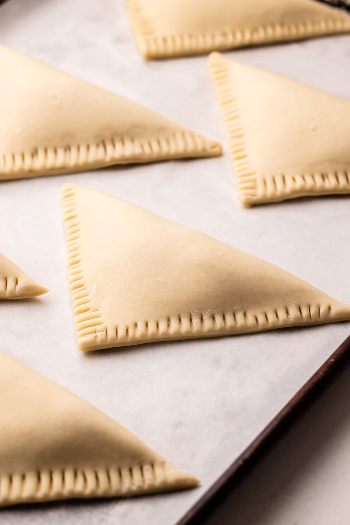 Unbaked and assembled turnovers on a white piece of parchment.