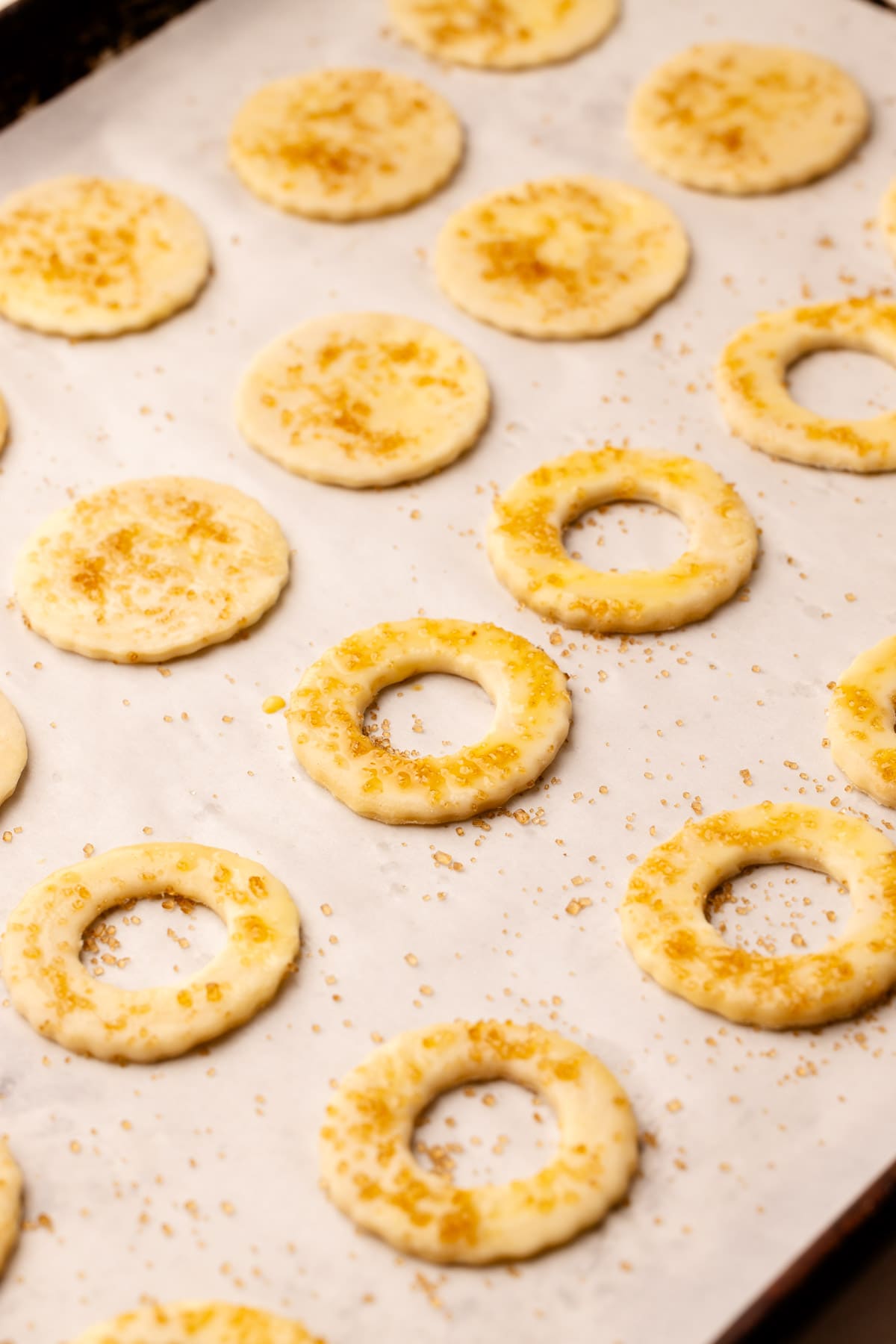 Cut out pie crust cookies on a sheet pan with egg wash and turbinado sugar.