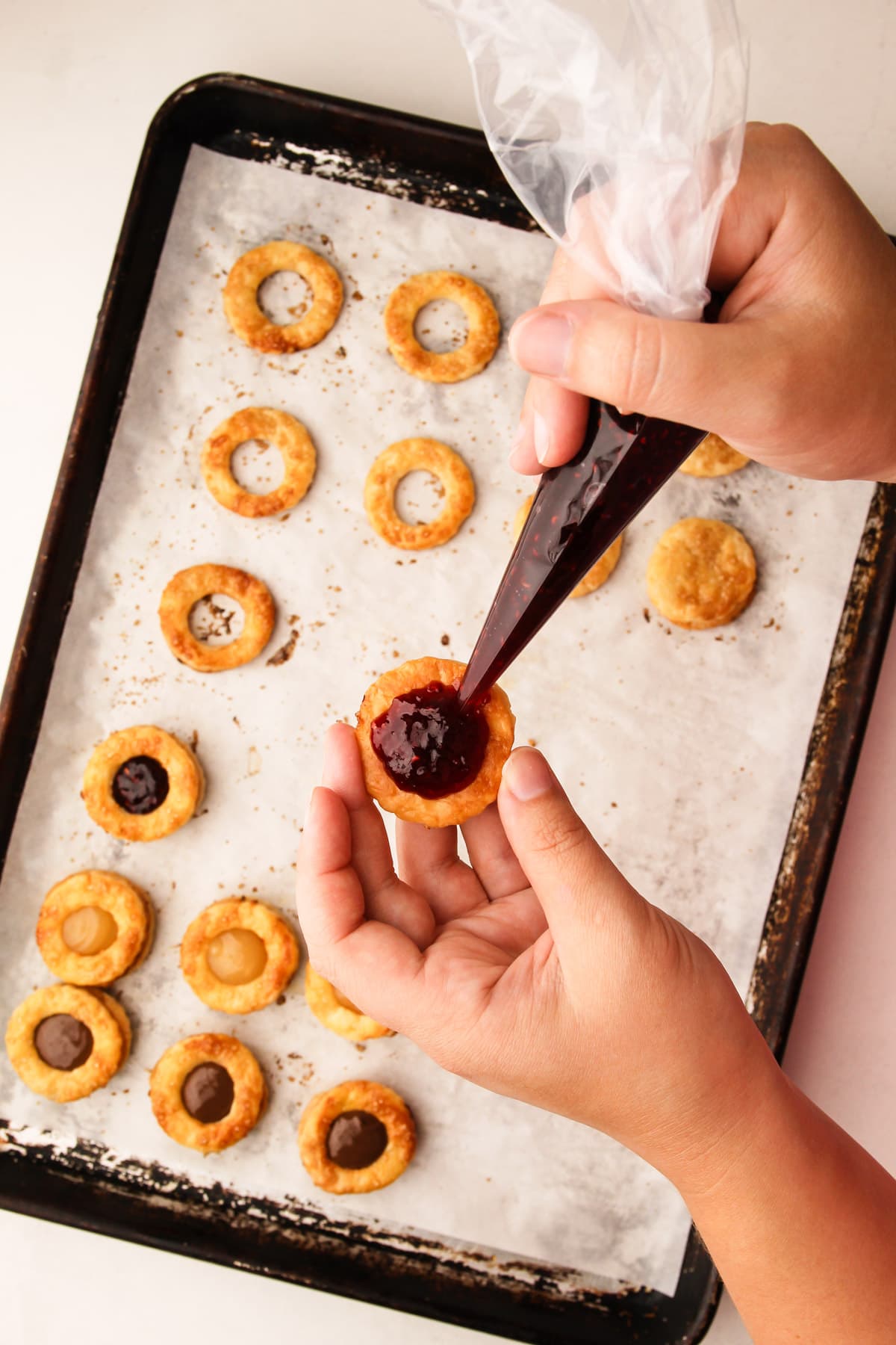 Filling pie crust cookies with jam.