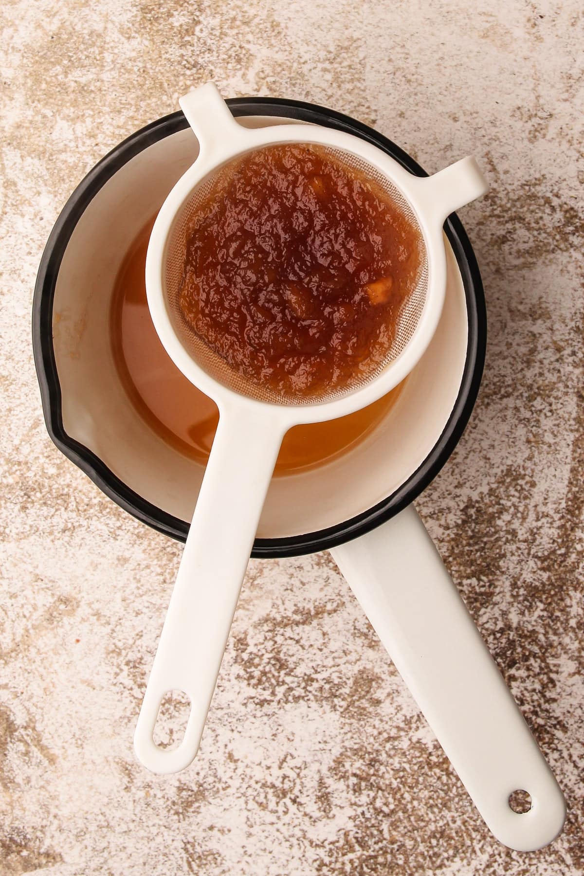 Straining apple jelly to make a glaze.