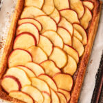 A fully baked and glazed apple tart on puff pastry.