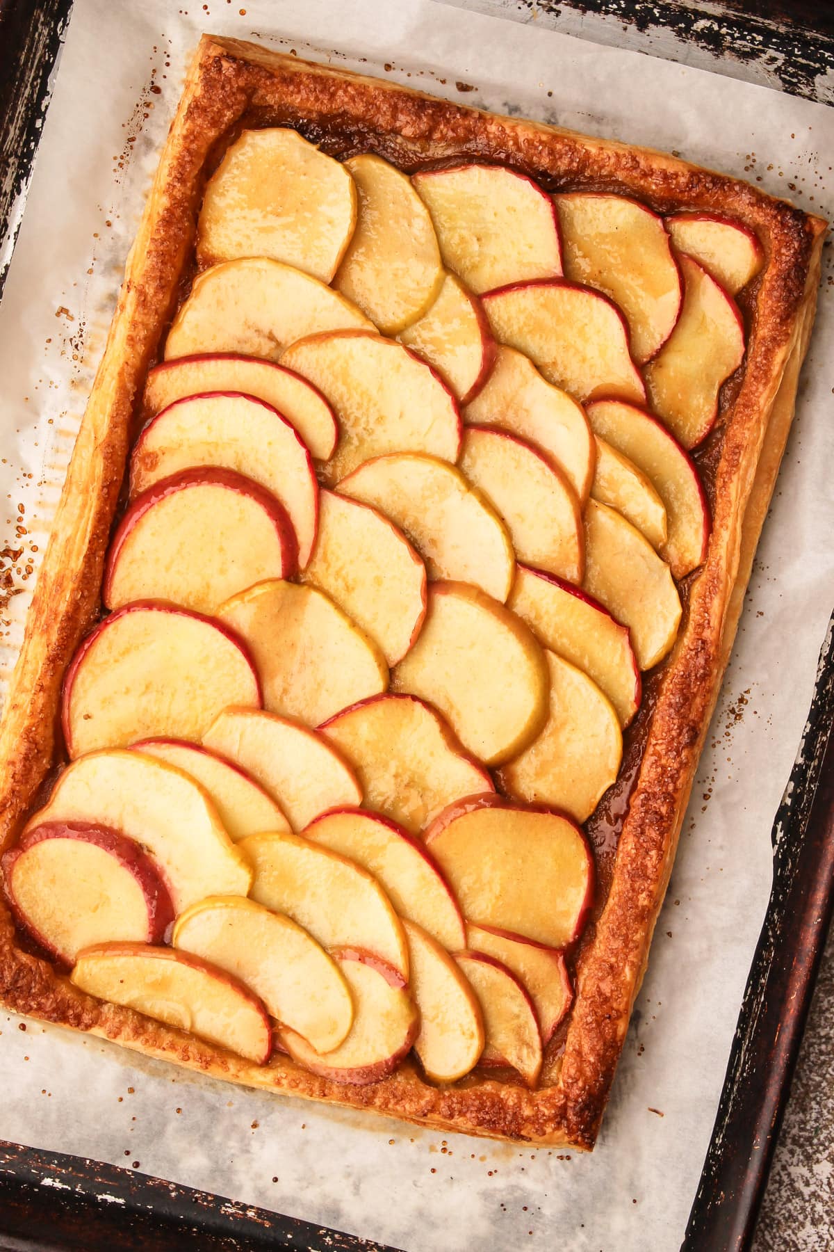 A fully baked and glazed apple tart on puff pastry.