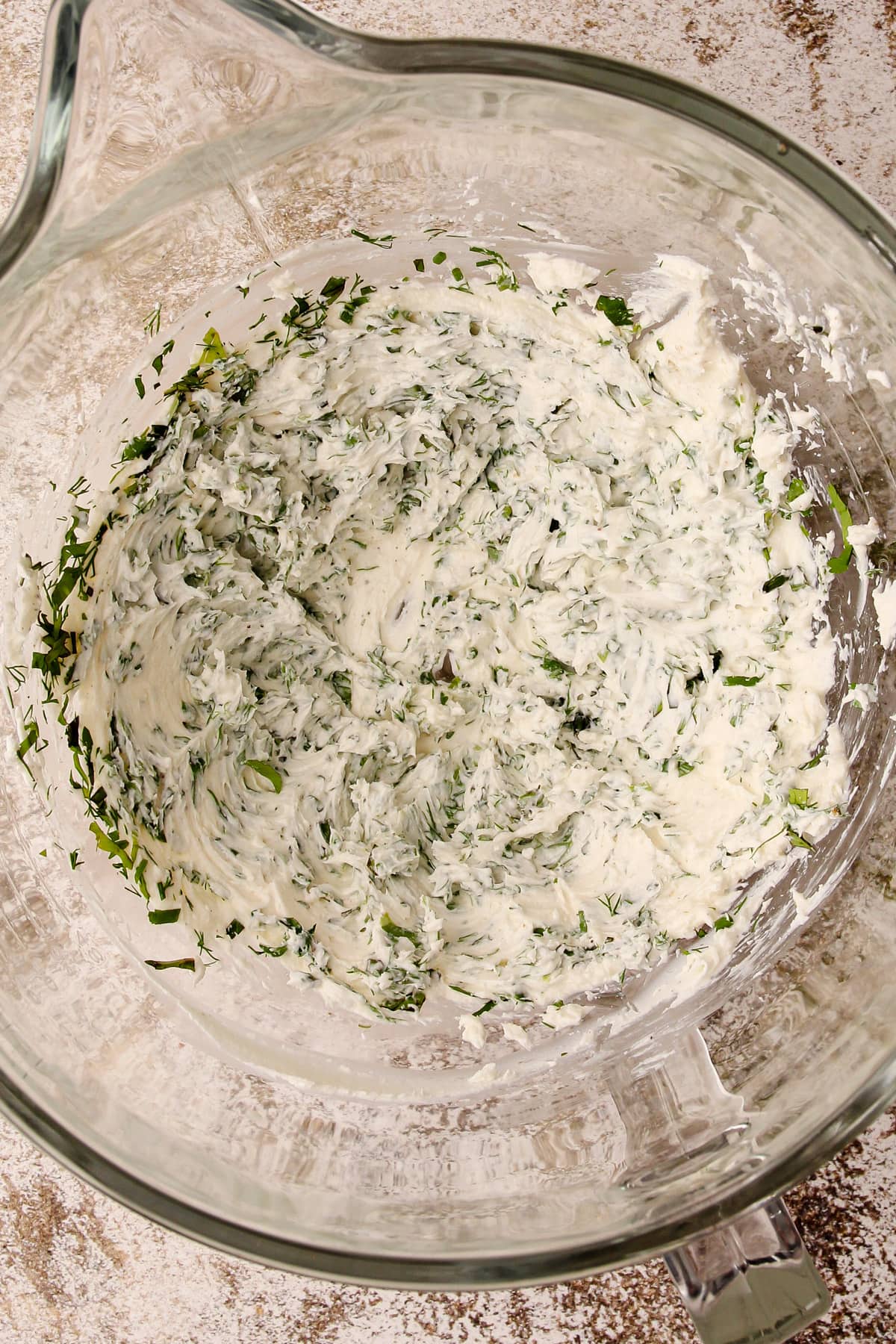 Goat cheese with herbs in a mixing bowl.