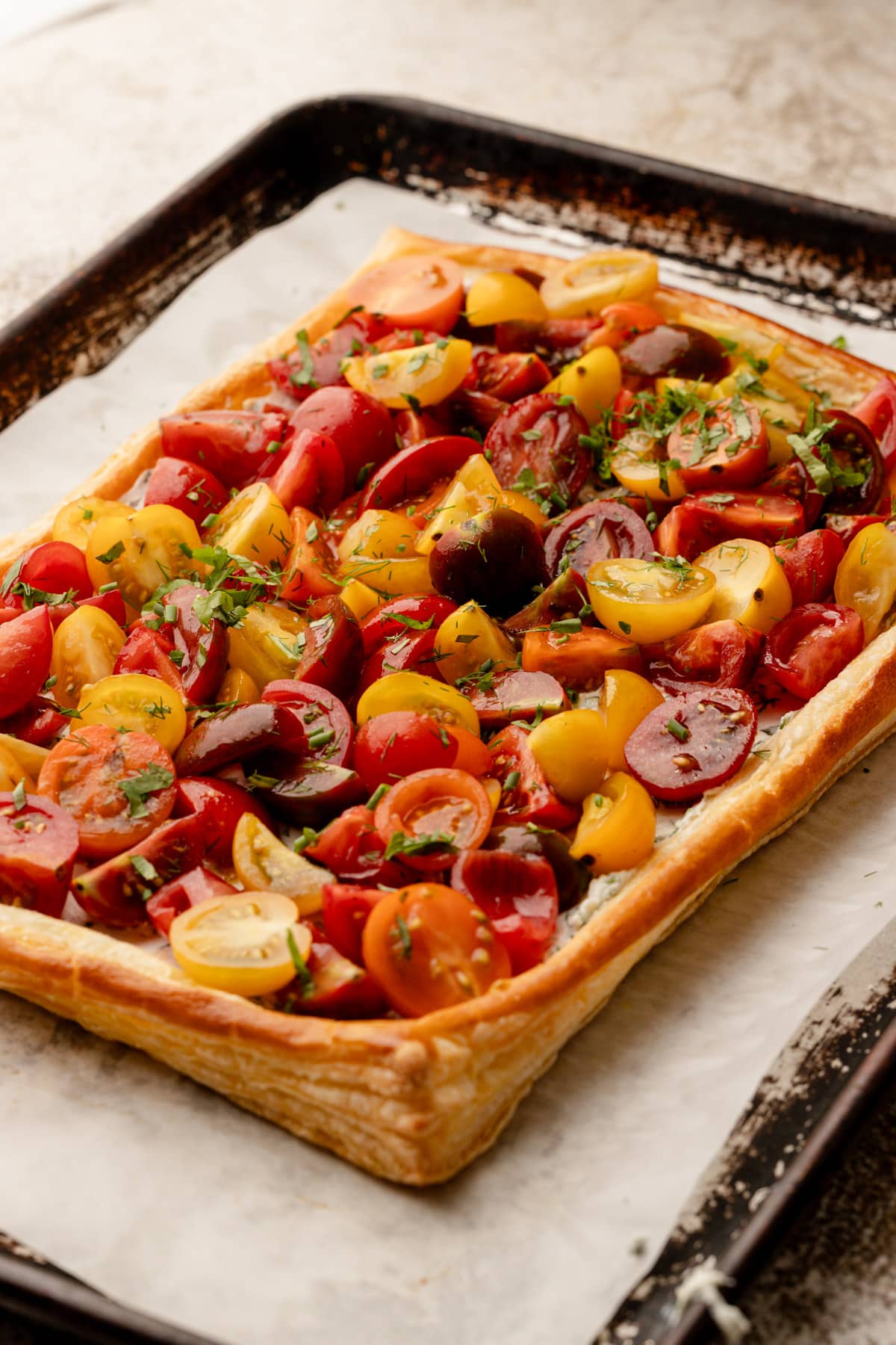 A full tomato tart on puff pastry before it has been sliced.