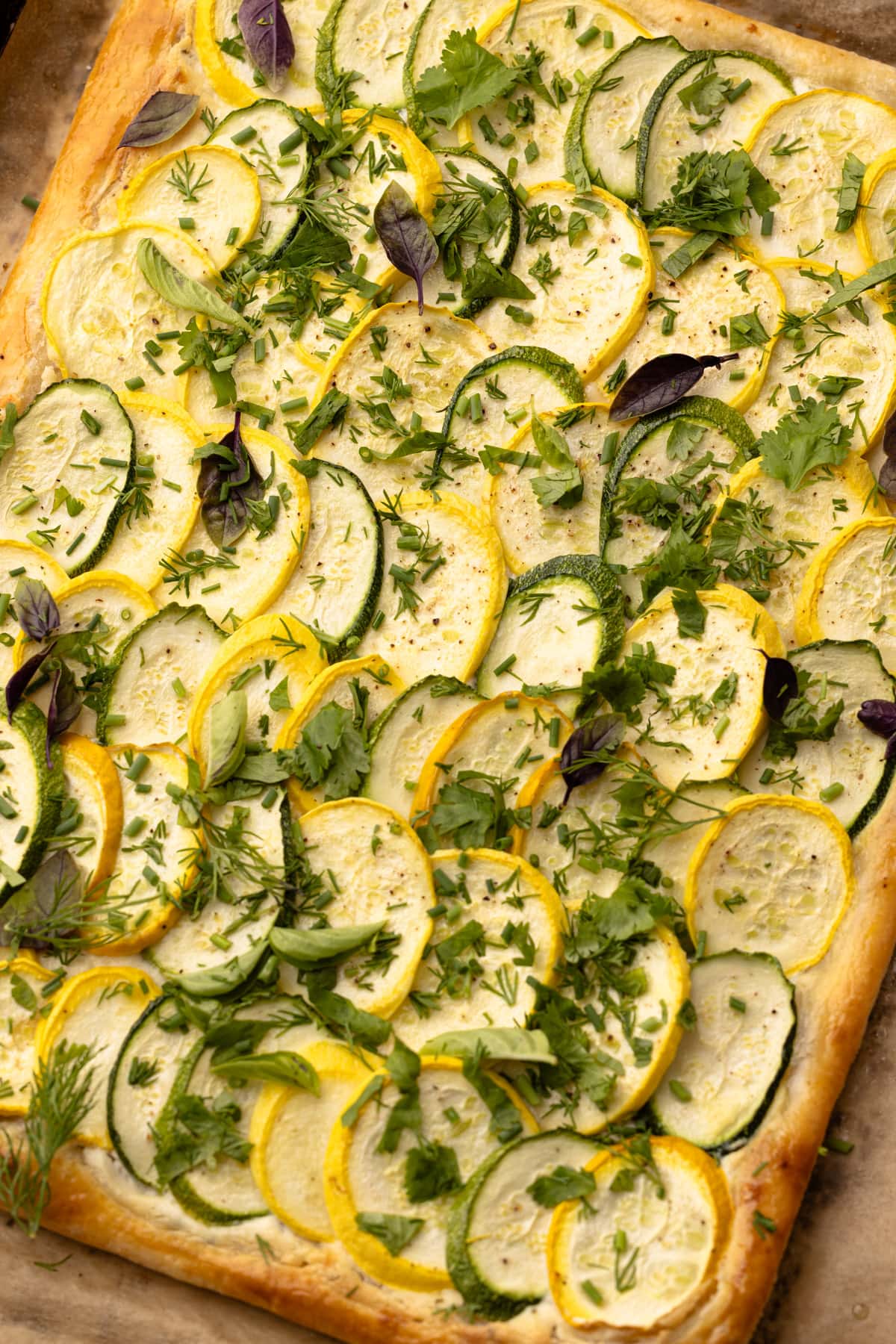 Puff pastry zucchini tart with herbs on a sheet tray.