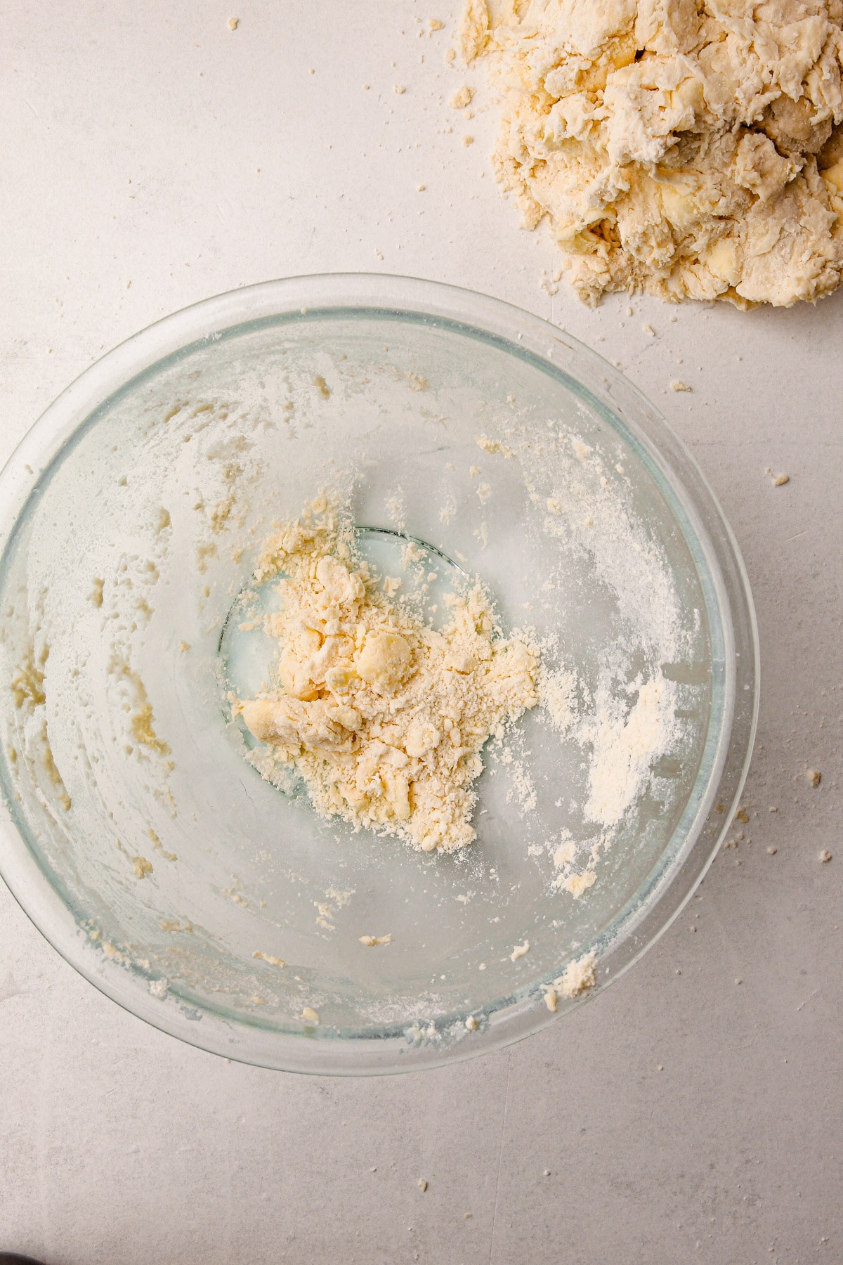 A small amount of butter and flour mixed together in a large glass bowl, with a large mound of more butter-flour mixture off to the side on the counter