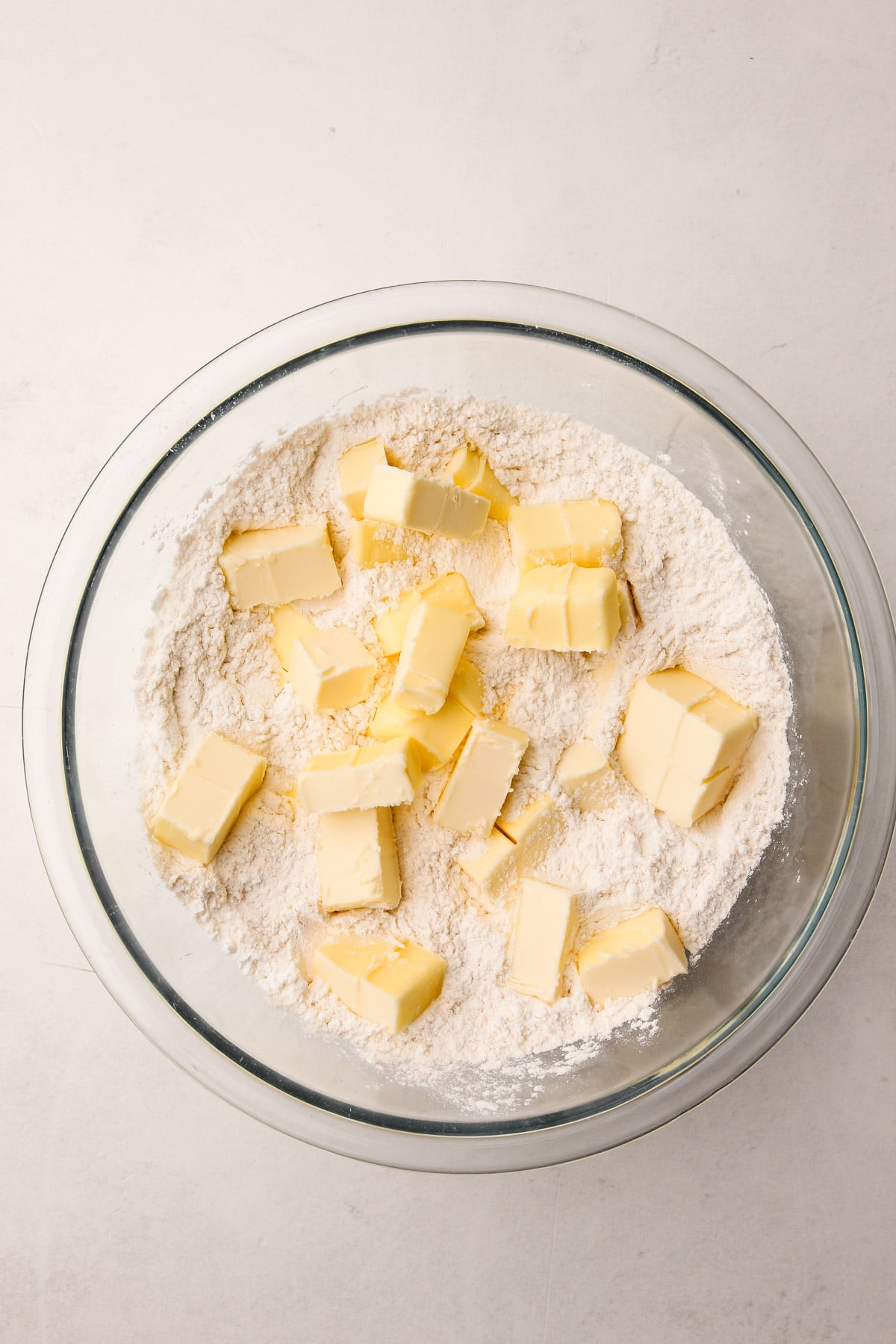 A glass bowl with flour and cubes of butter in it