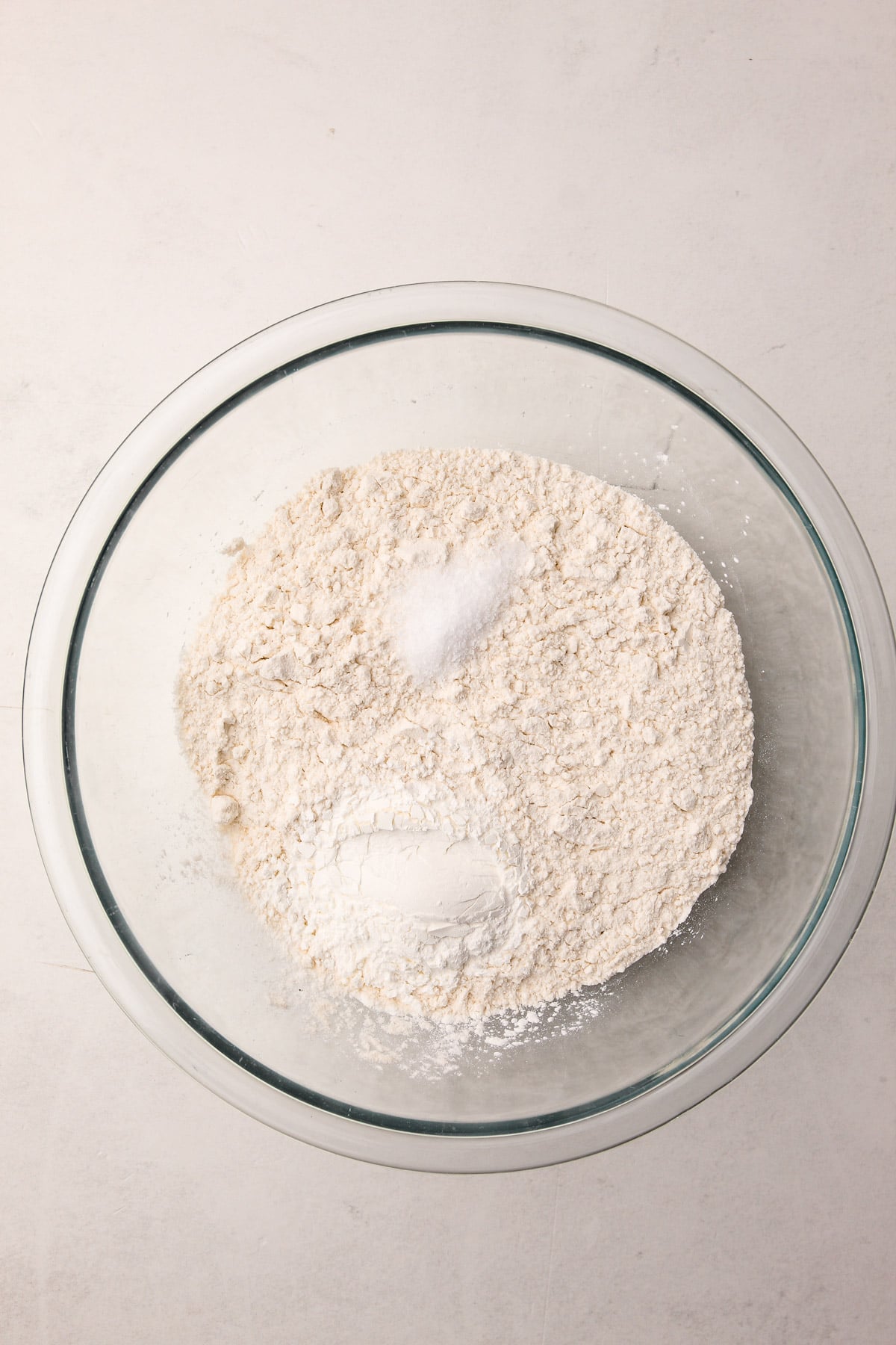 A glass bowl with flour, cornstarch, and salt in it.