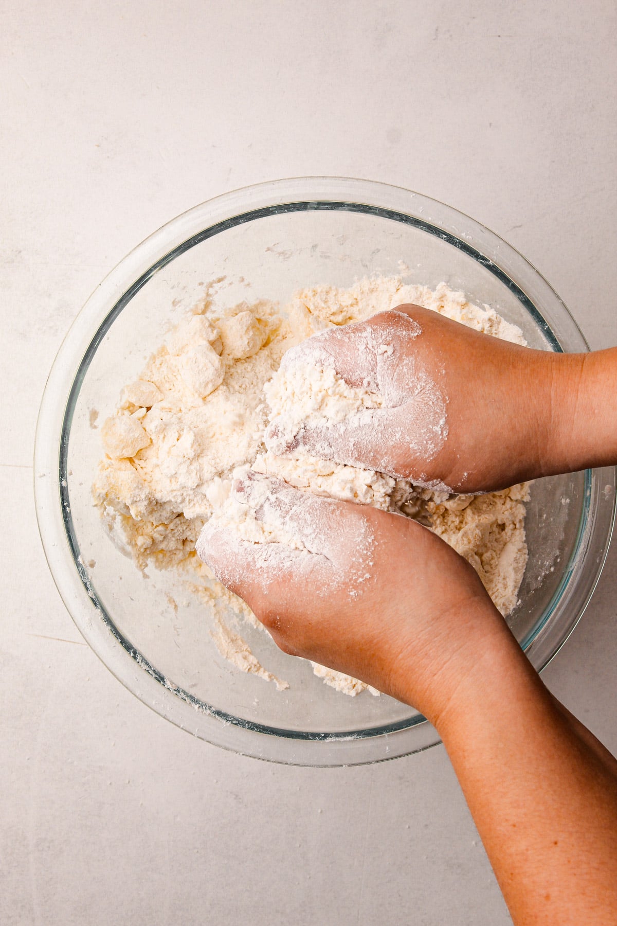 Two hands rubbing a mixture of flour and butter together over a bowl with more flour and butter in it