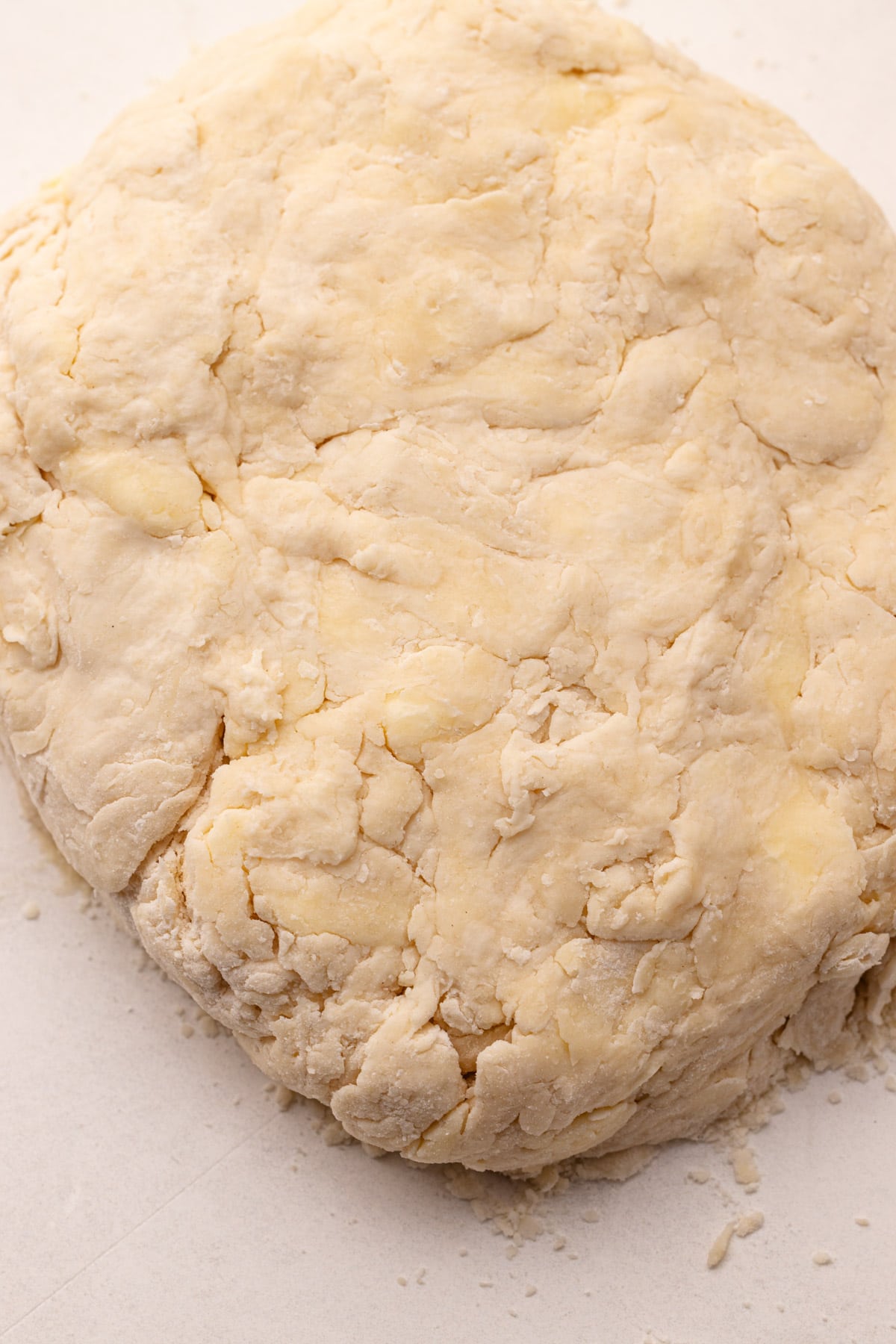 A close-up of a round of pie dough, with lumps of butter distributed throughout