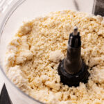 A crumbly mixture of flour and butter in the bowl of a food processor