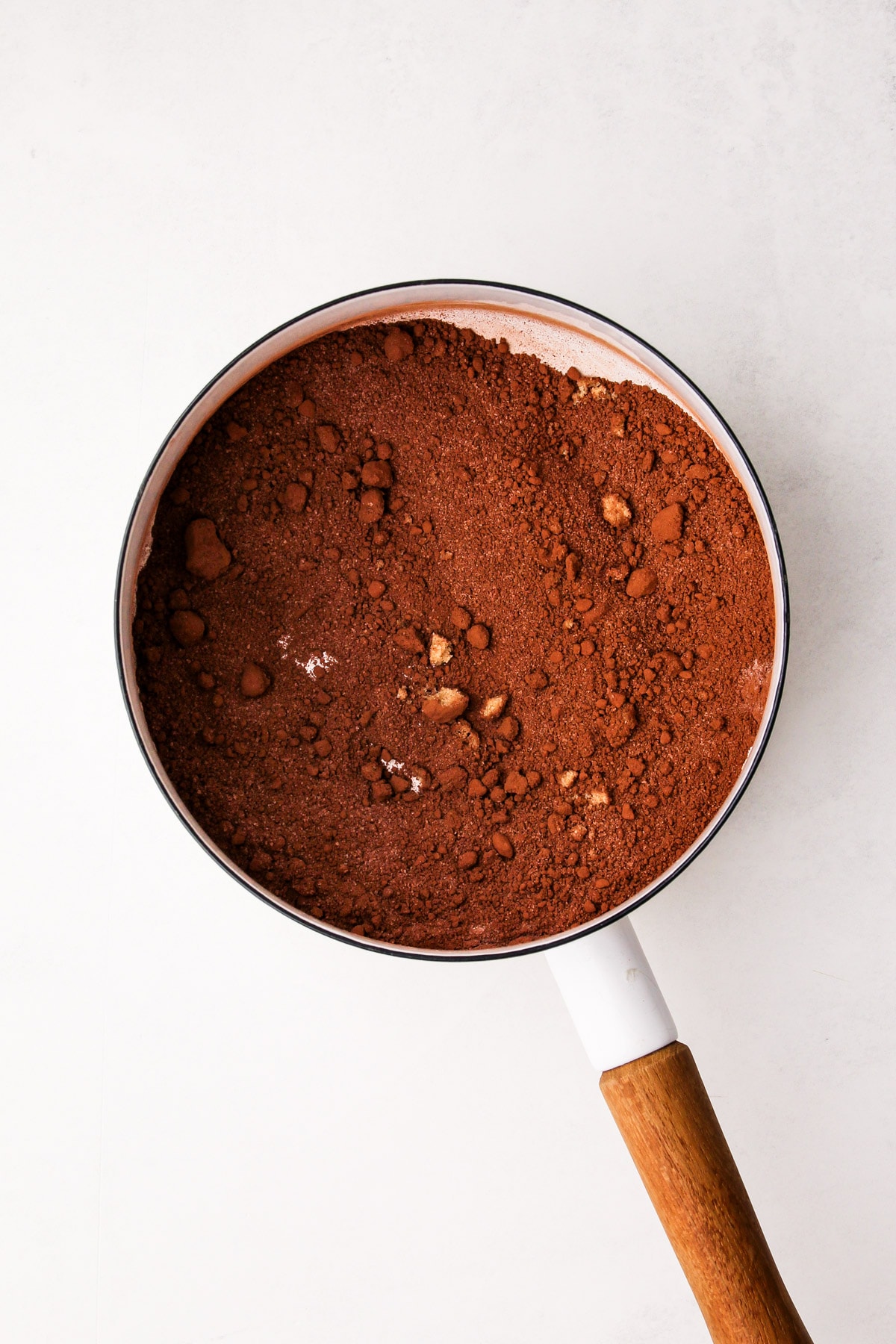 A pot with cocoa powder and sugar stirred together in it