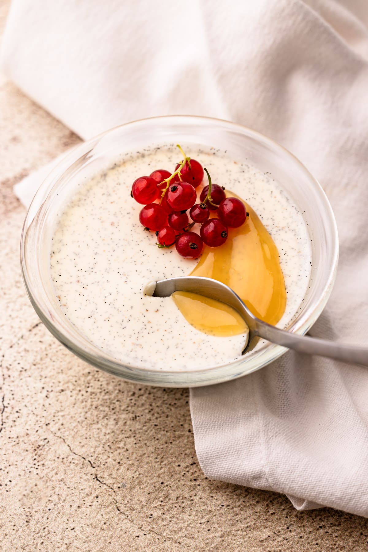 A bowl with set panna cotta with a spoon taking a bite from it.