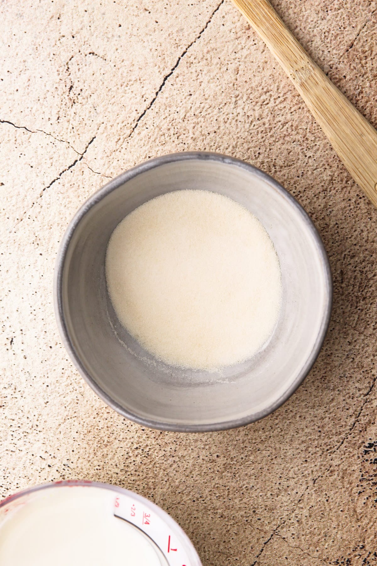 A small gray bowl with granular gelatin to make vanilla panna cotta.