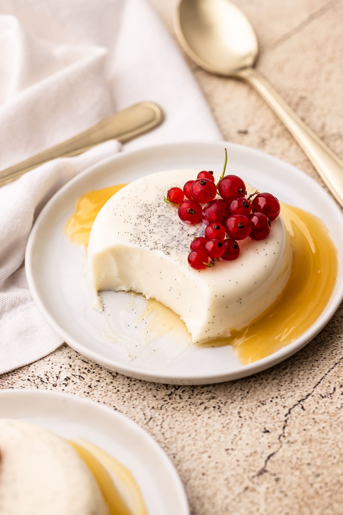 A plate of vanilla bean panna cotta with a bite taken to reveal the creamy interior.