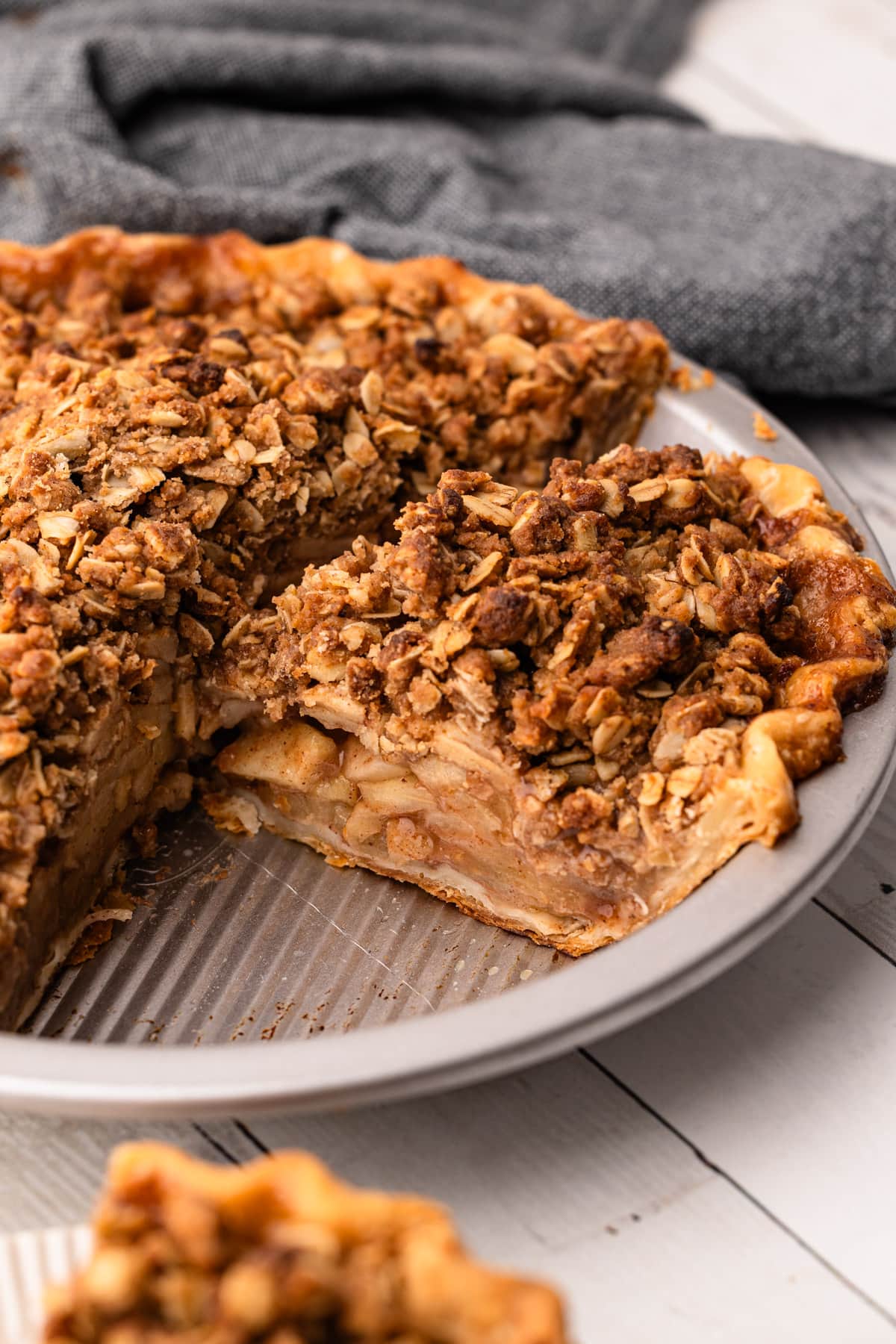 An apple crumb pie being served from the metal pie tin.
