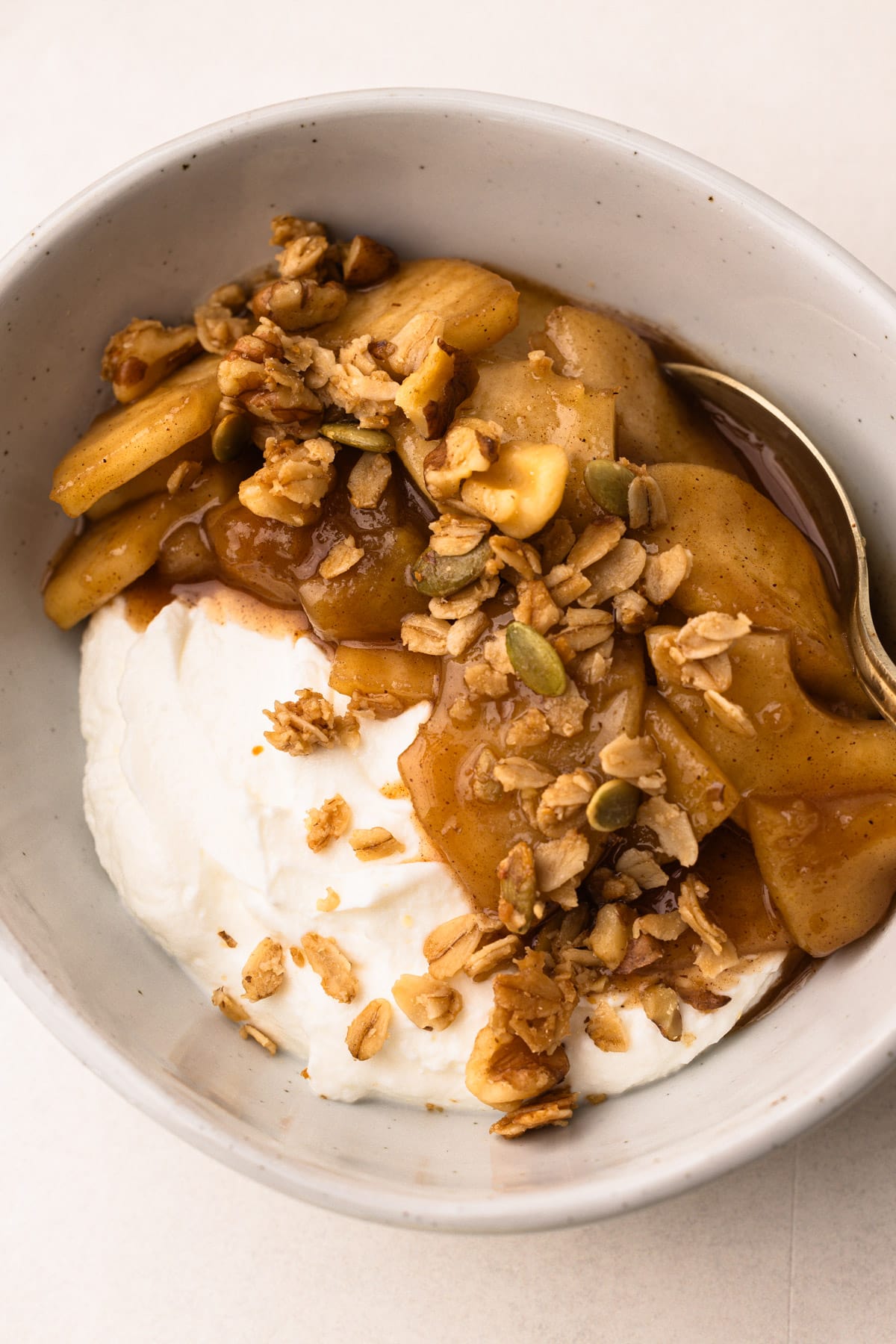 Un bol avec du yaourt, du granola et de la garniture de tarte aux pommes.