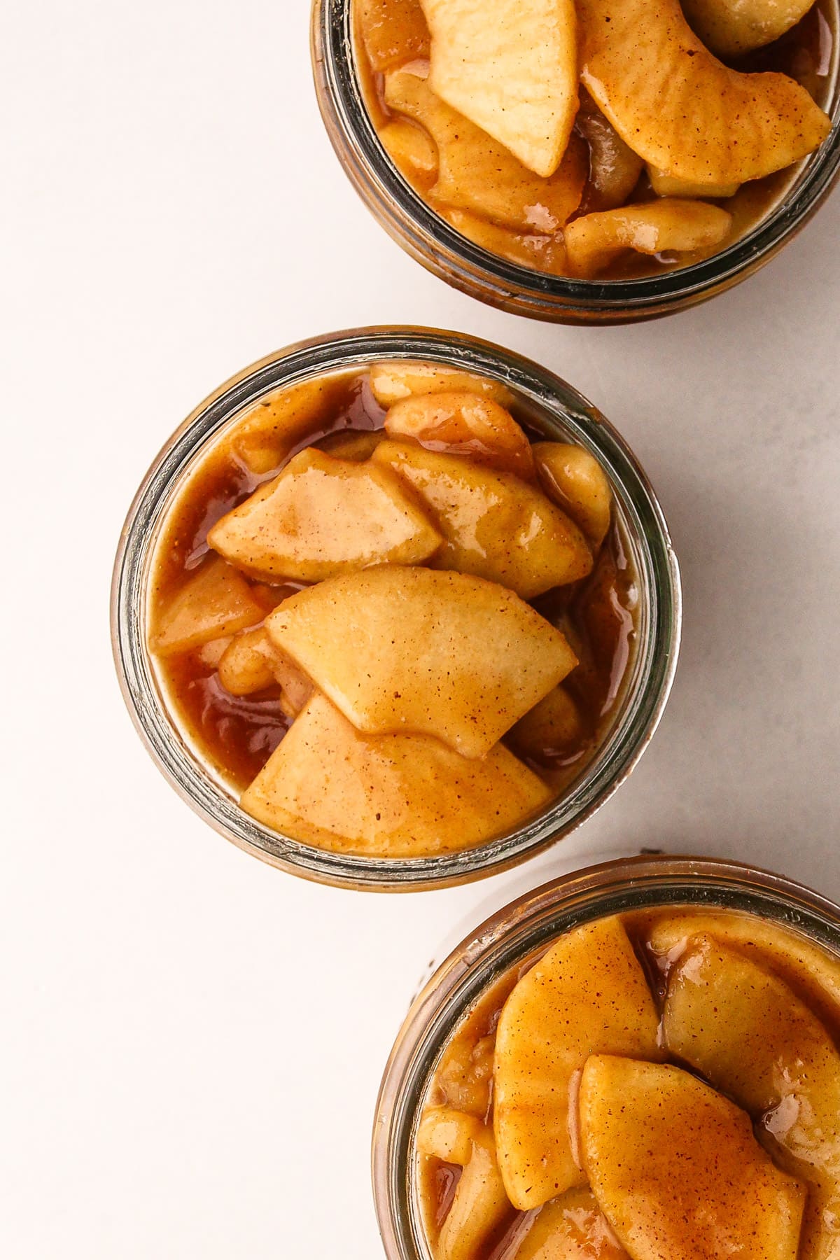 Three jars with prepared apple pie filling.