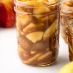A side view of a filled jar of apple pie filling already cooked.