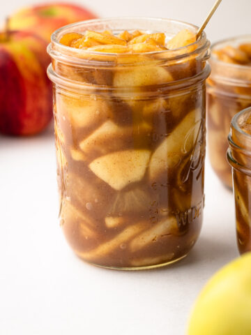 A side view of a filled jar of apple pie filling already cooked.