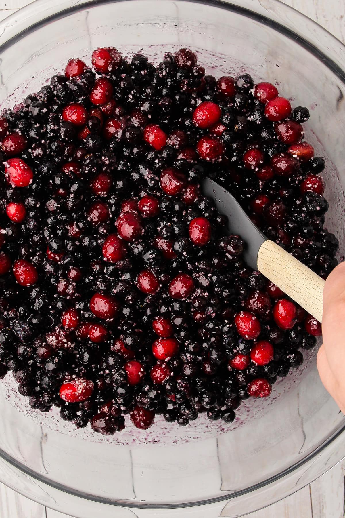 A bowl with the filling ingredients for Blueberry-Cranberry Pie in it, with a rubber spatula.