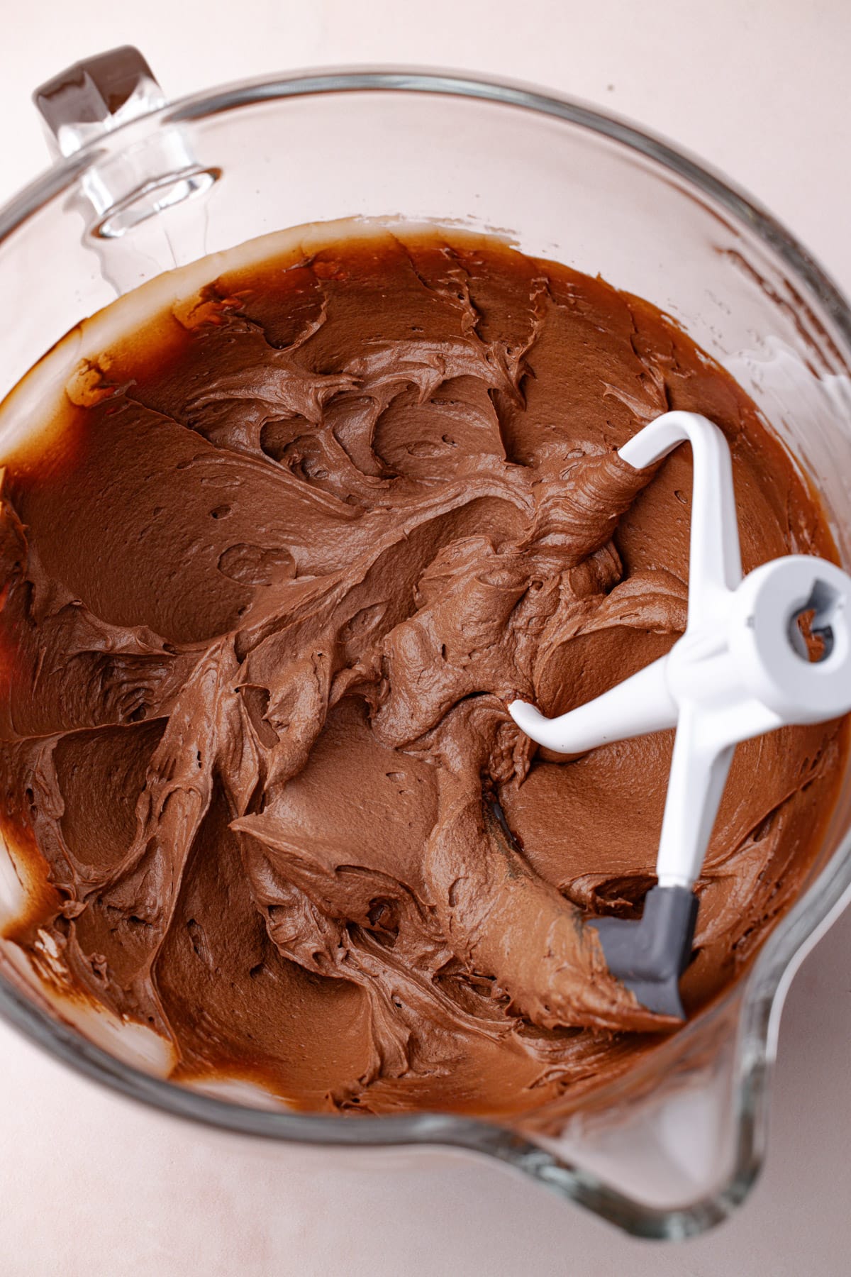 Whipped chocolate ganache in the bowl of a stand mixer with the paddle attachment.