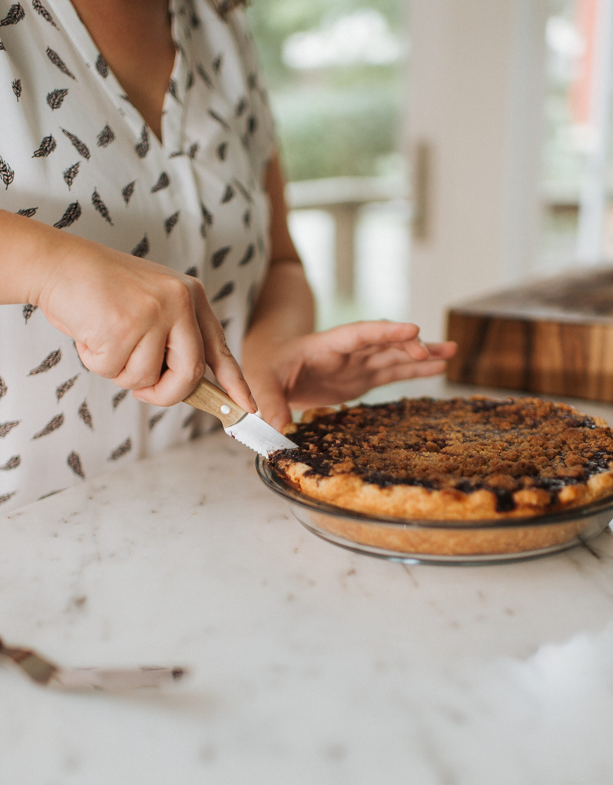 Kelli cutting into a pie with a serrated knife.