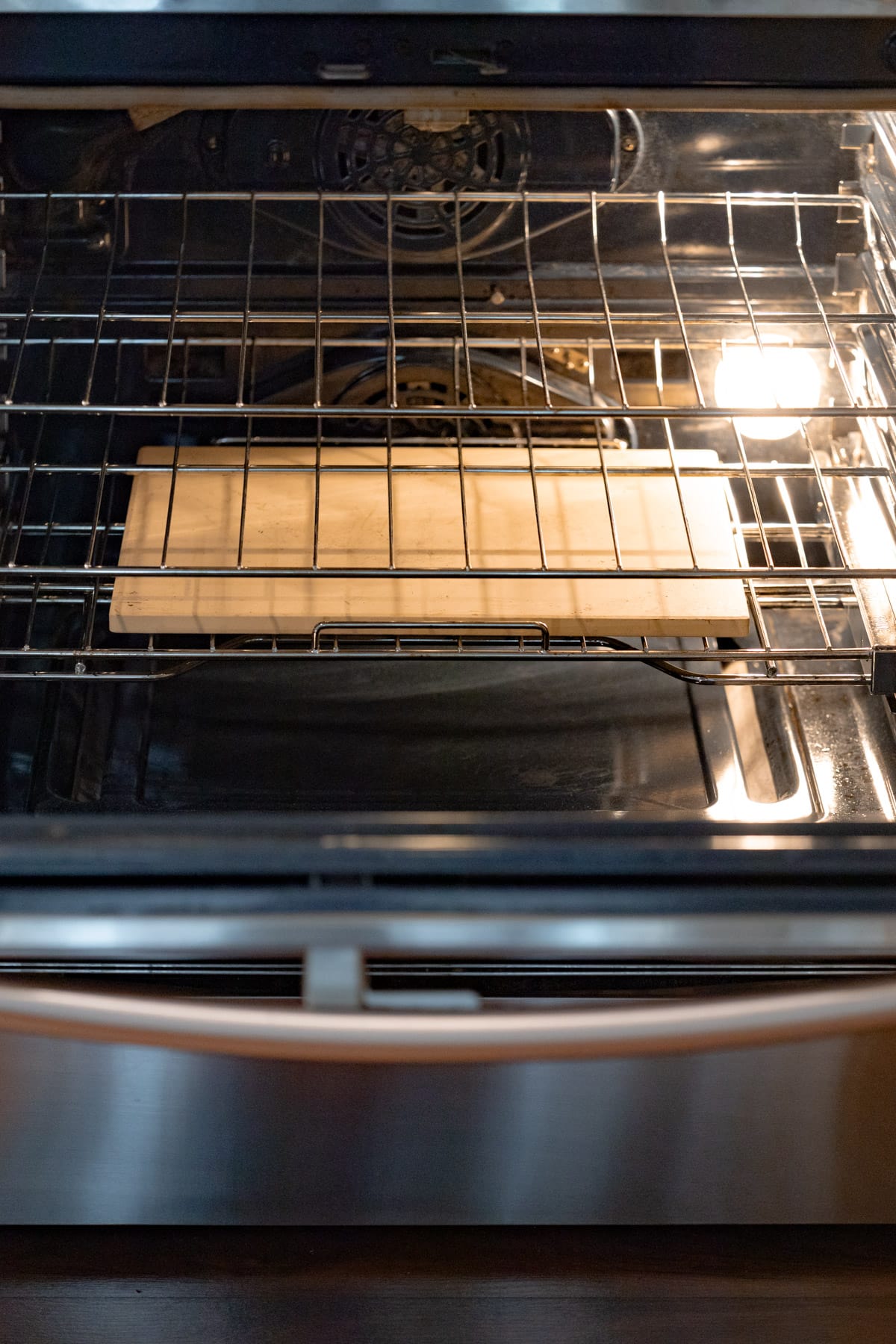 A baking stone on an oven rack inside an oven, used as a pie baking tool.