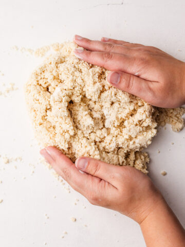 Hands bringing together pie dough.