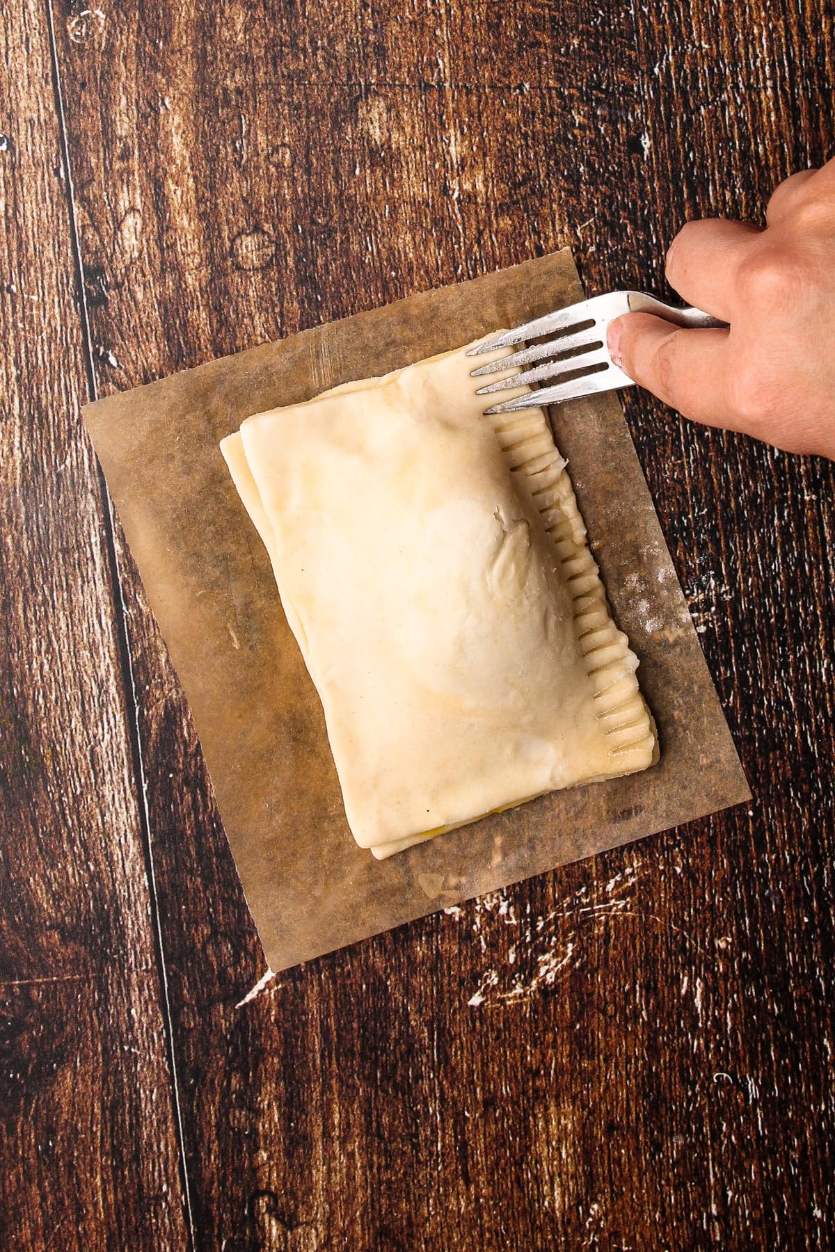 Using a fork to seal the edges of the unbaked turkey pot pie.