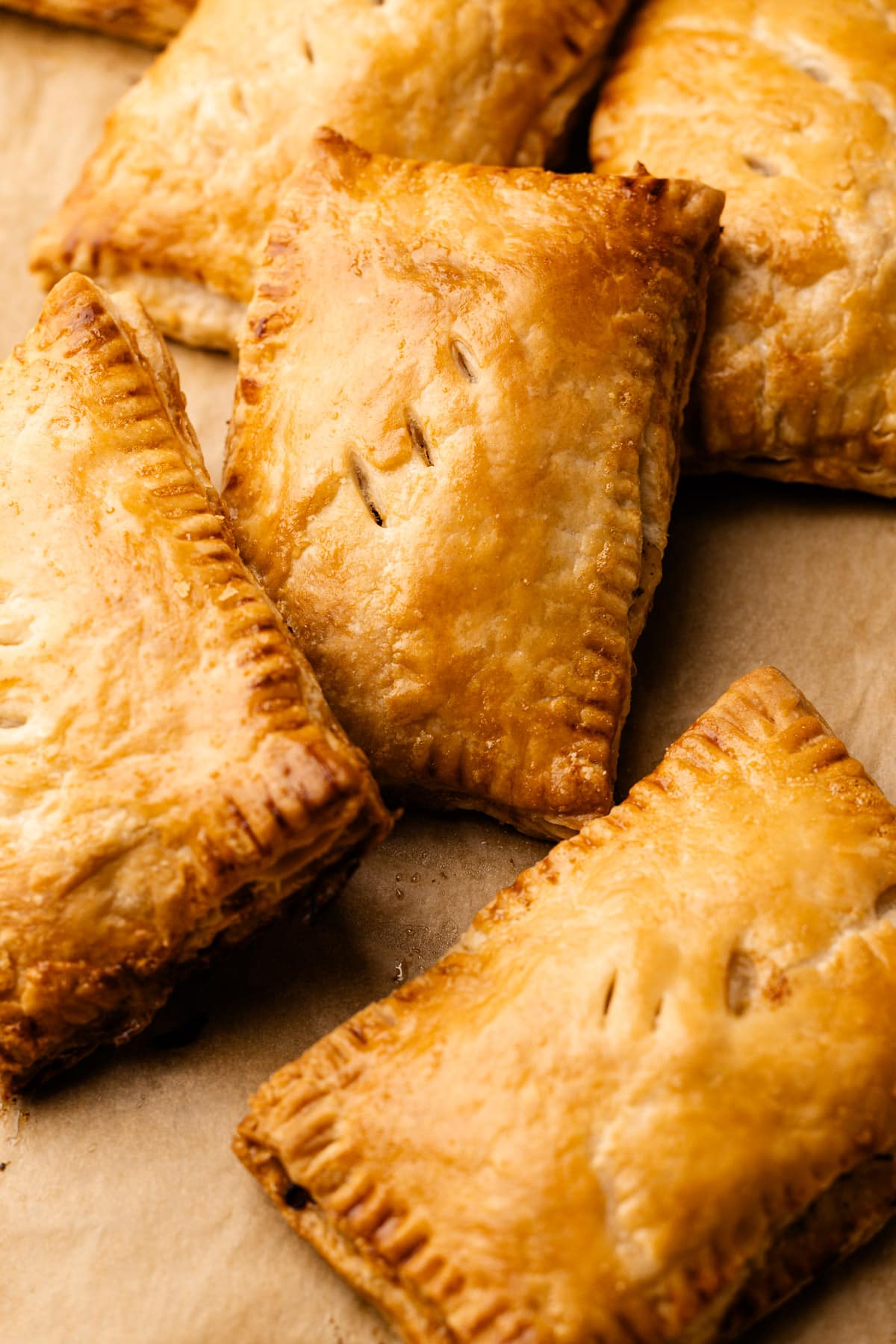 Many turkey hand pies fully baked laid out on a sheet tray.