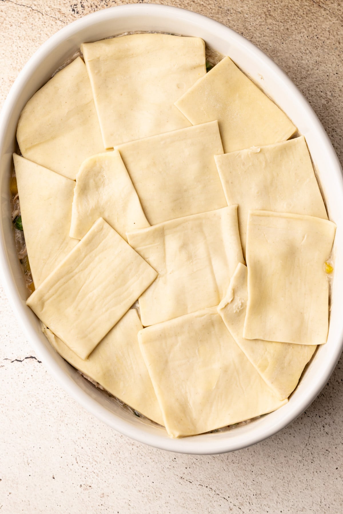 Raw puff pastry pieces laid on top of turkey pot pie filling.