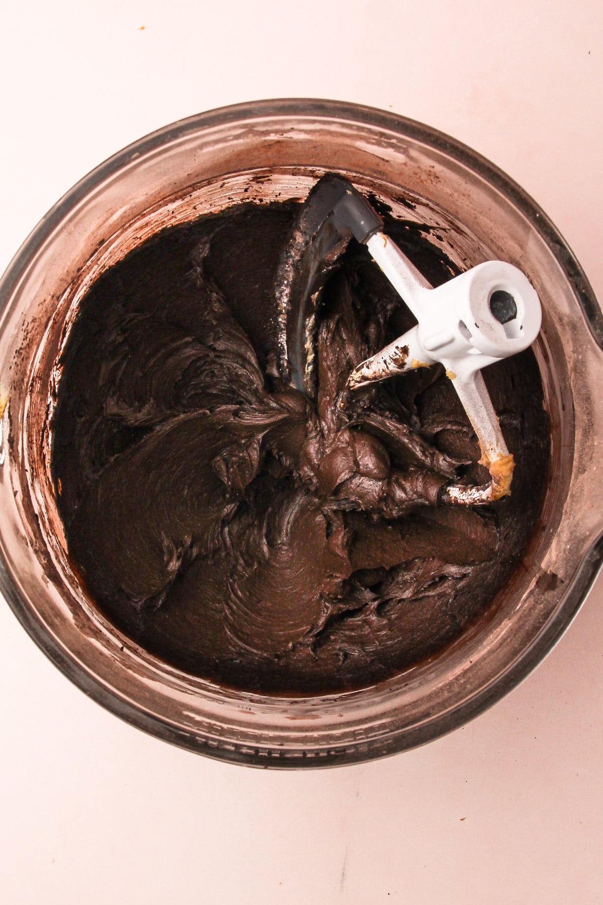 Dough for chocolate shortbread cookies in a stand mixer bowl with the paddle attachment.